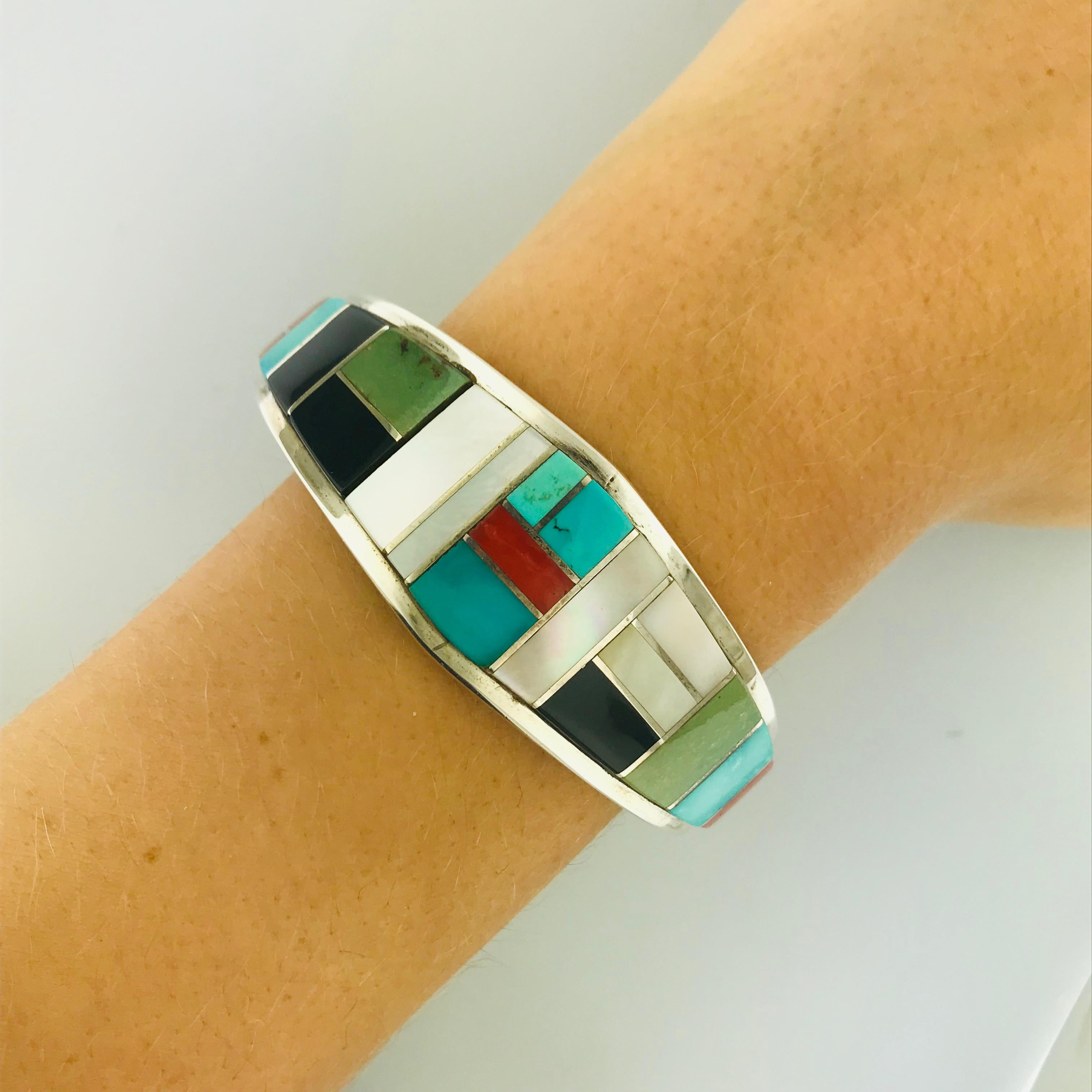 A beautifully Zuni hand-crafted genuine gemstone cuff. Made with rich genuine turquoise, deep coral, mother of pearl, spiny oyster and black onyx, set in a high polish, bright sterling silver. The cuff is a bold and beautiful piece that can fit on a