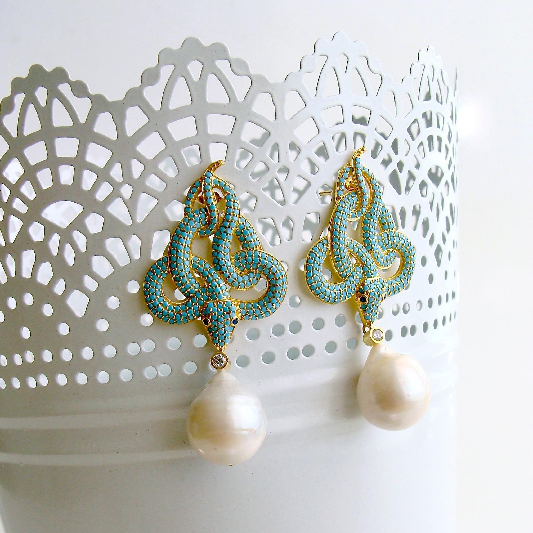 A unique pair of intertwined snake earrings, reminiscent of the Victorian style, is covered in pave set turquoise crystal and dangles with generous baroque freshwater pearls.  These post-style earrings are clearly not for the faint of heart and