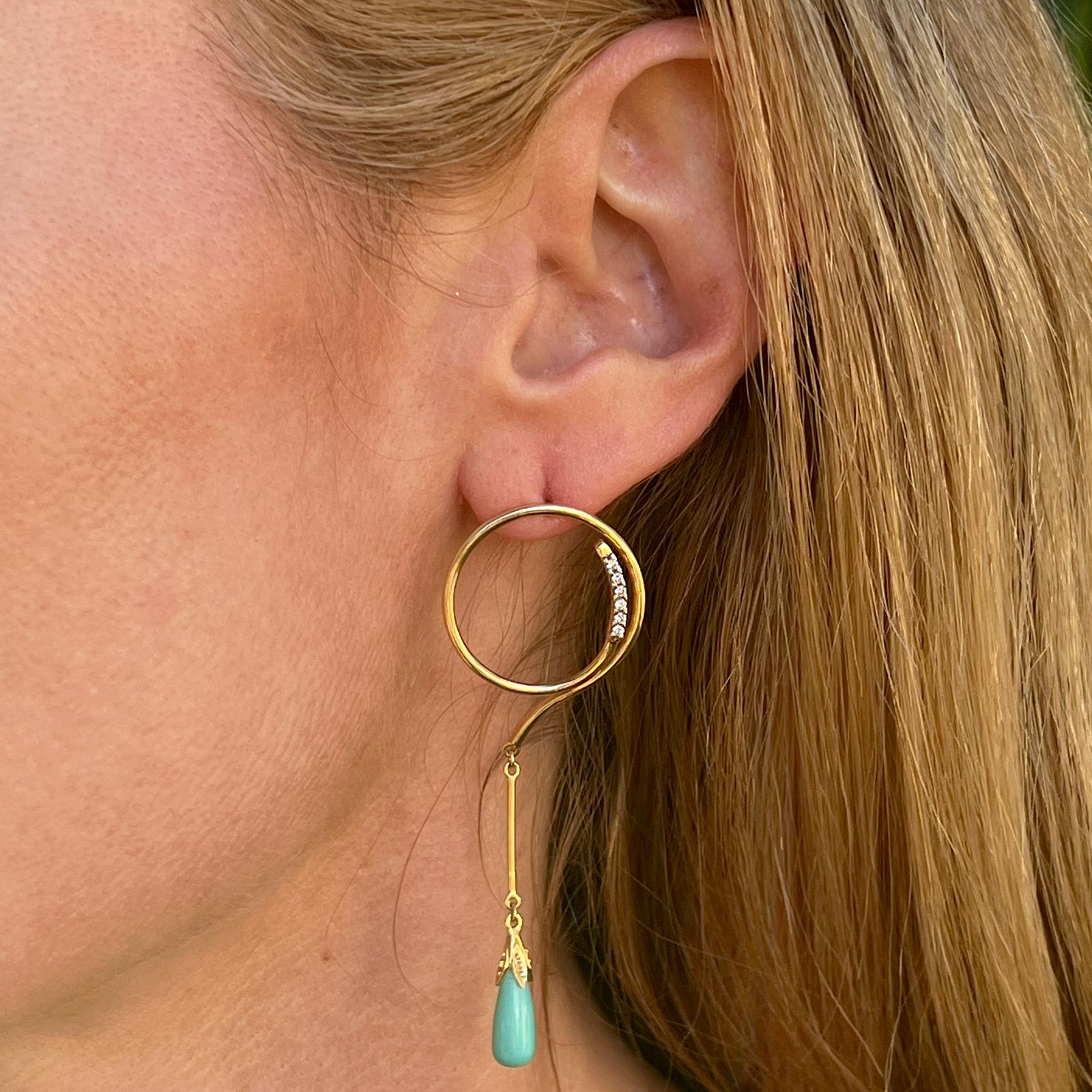 Turquoise and diamond drop earrings crafted in 18 karat yellow gold. The earrings feature open circle tops set with 12 round brilliant cut diamonds weighing approximately .12 CTW and graded H-I color and SI clarity. The gold thin drops are set with
