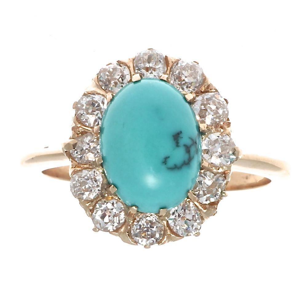 Stylishly timeless the halo ring has ingrained itself in jewelry as one of the most iconic creations. Featuring a vibrantly multihued bluish-green cabochon cut turquoise that is surrounded by a halo of old cut diamonds. Hand crafted in 18k gold.