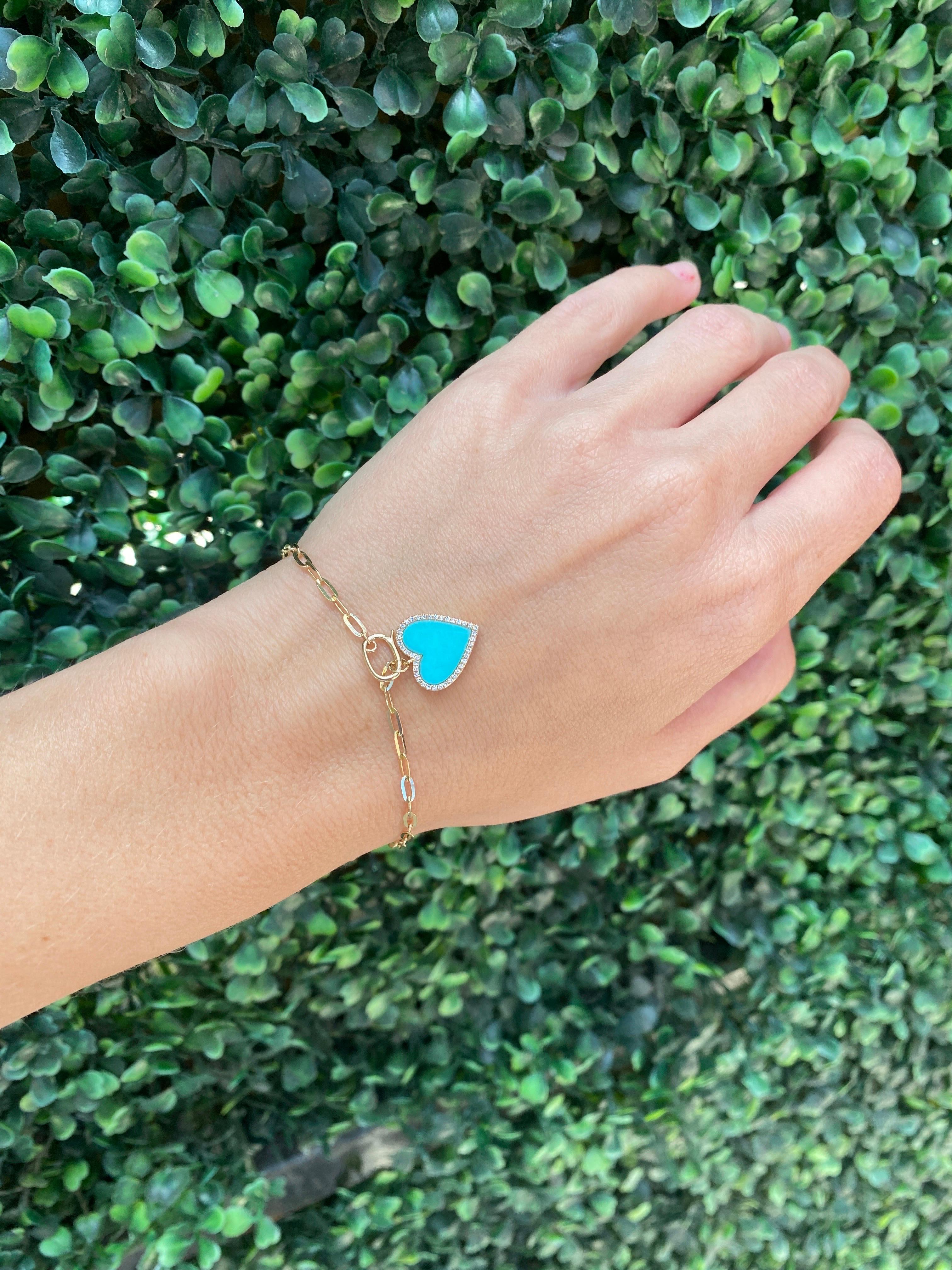 This 14 karat yellow gold bracelet features a turquoise heart with approximately 0.10 carat total weight in round diamonds that dangles from a link chain. 
Measurements: Length approximately 6.75