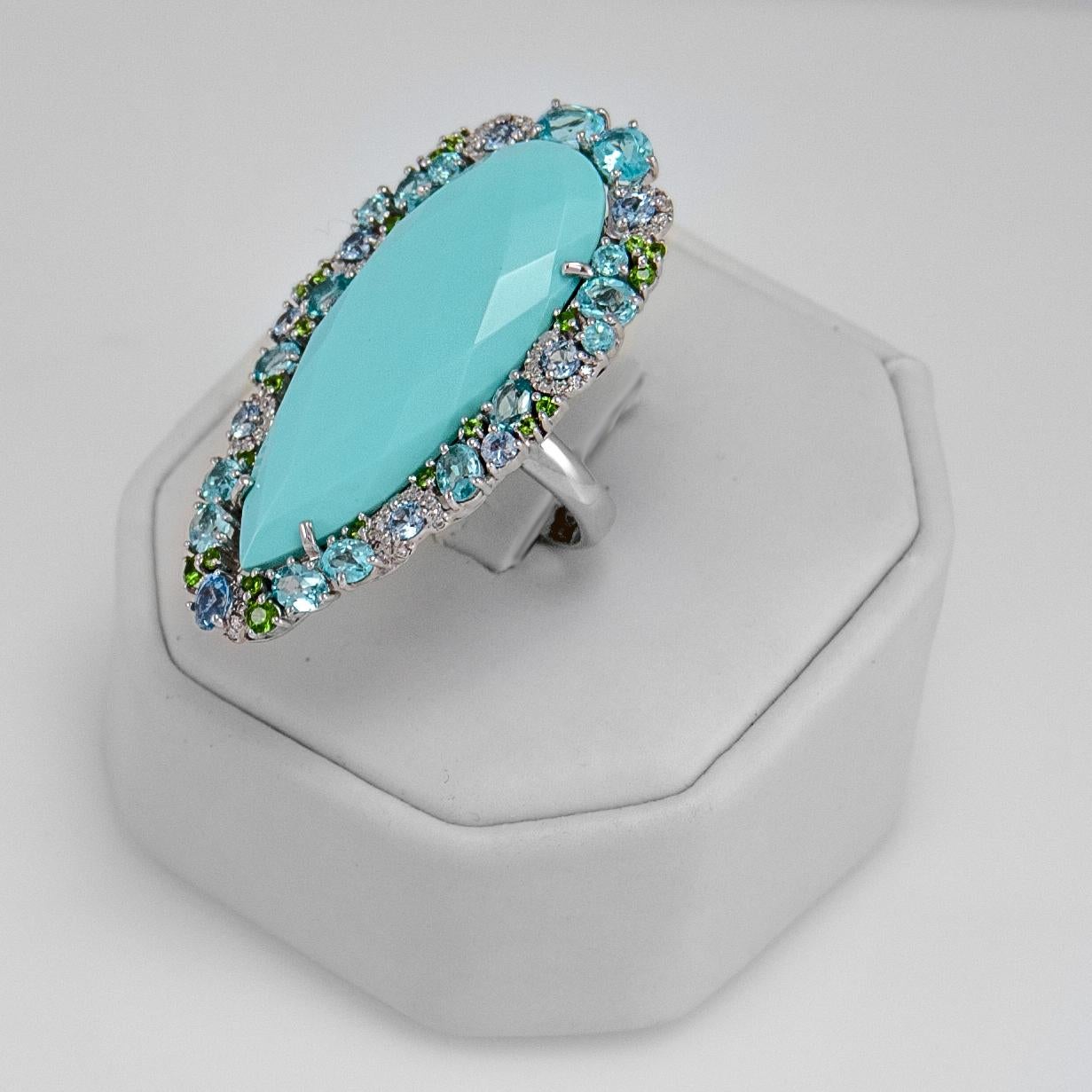 Elegant and delightful fashion turquoise ring bordered with blue topaz light blue sapphires tsavorites and diamonds.
Turquoise is pear shape and faceted for a unique shine and measures 1 1/2 by 5/8 inches (37 x 16 mm) and weighs 18.25 carats.
Blue