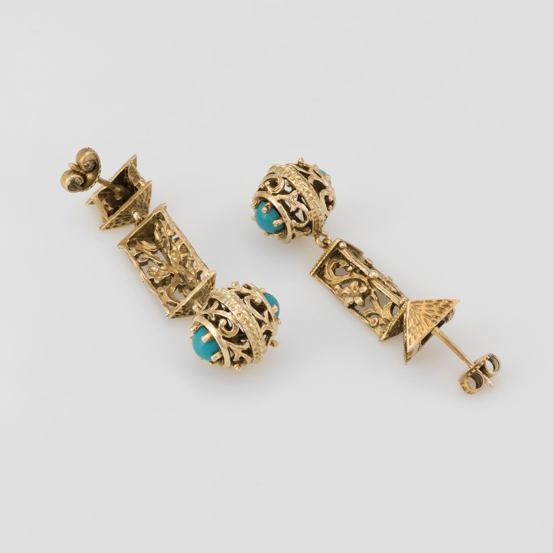 Finely detailed pair of vintage drop earrings (circa 1960s to 1970s), crafted in 14k yellow gold. 

Four pieces of turquoise are embedded into the drop mounts. The turquoise is in excellent condition and free of cracks or chips.   

The charming