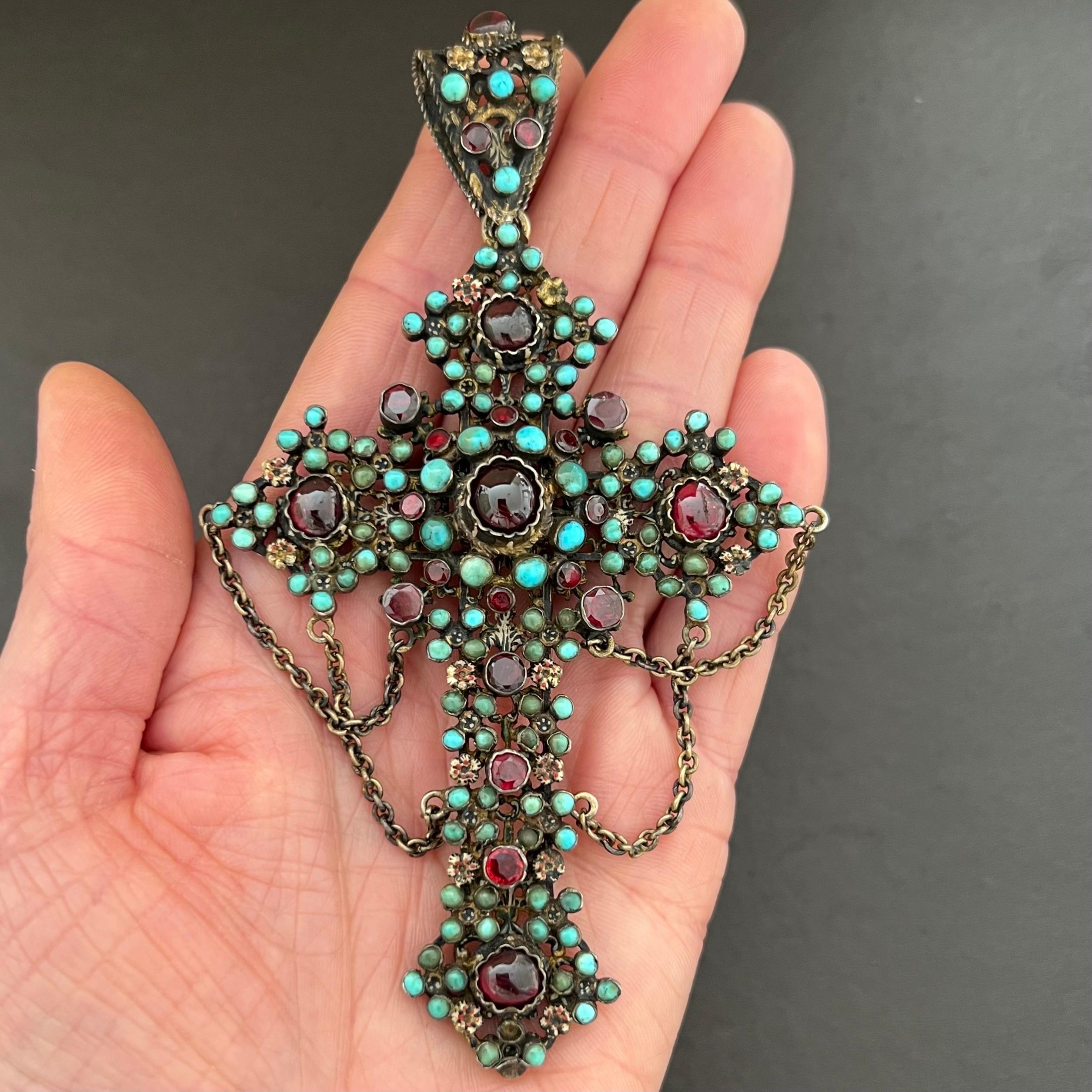 This large 1860's Austro-Hungarian antique cross pendant is set with many turquoise and garnet gemstones. The four cabochon cut garnet stones on front of the cross are all set in raised cut down collets, the other garnet stones are faceted and bezel