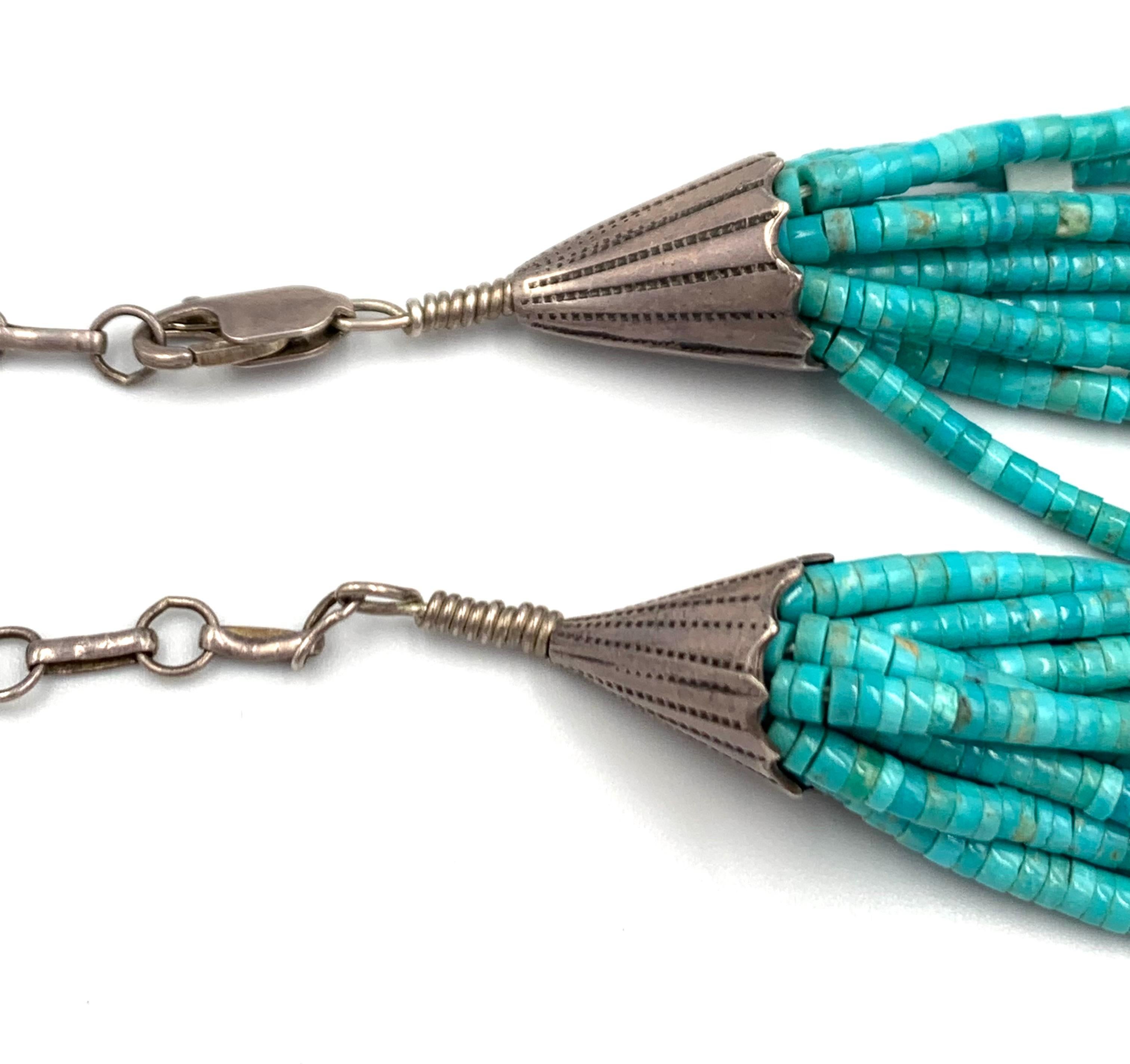 Ten strands of hand rolled turquoise heishi beads. Each of the 18” strands are interspersed with jet and coral beads. The strands are gathered by 1 ¼” silver cones with a 4” extension for a total length of 23”.

For hundreds of years, Santo Domingo