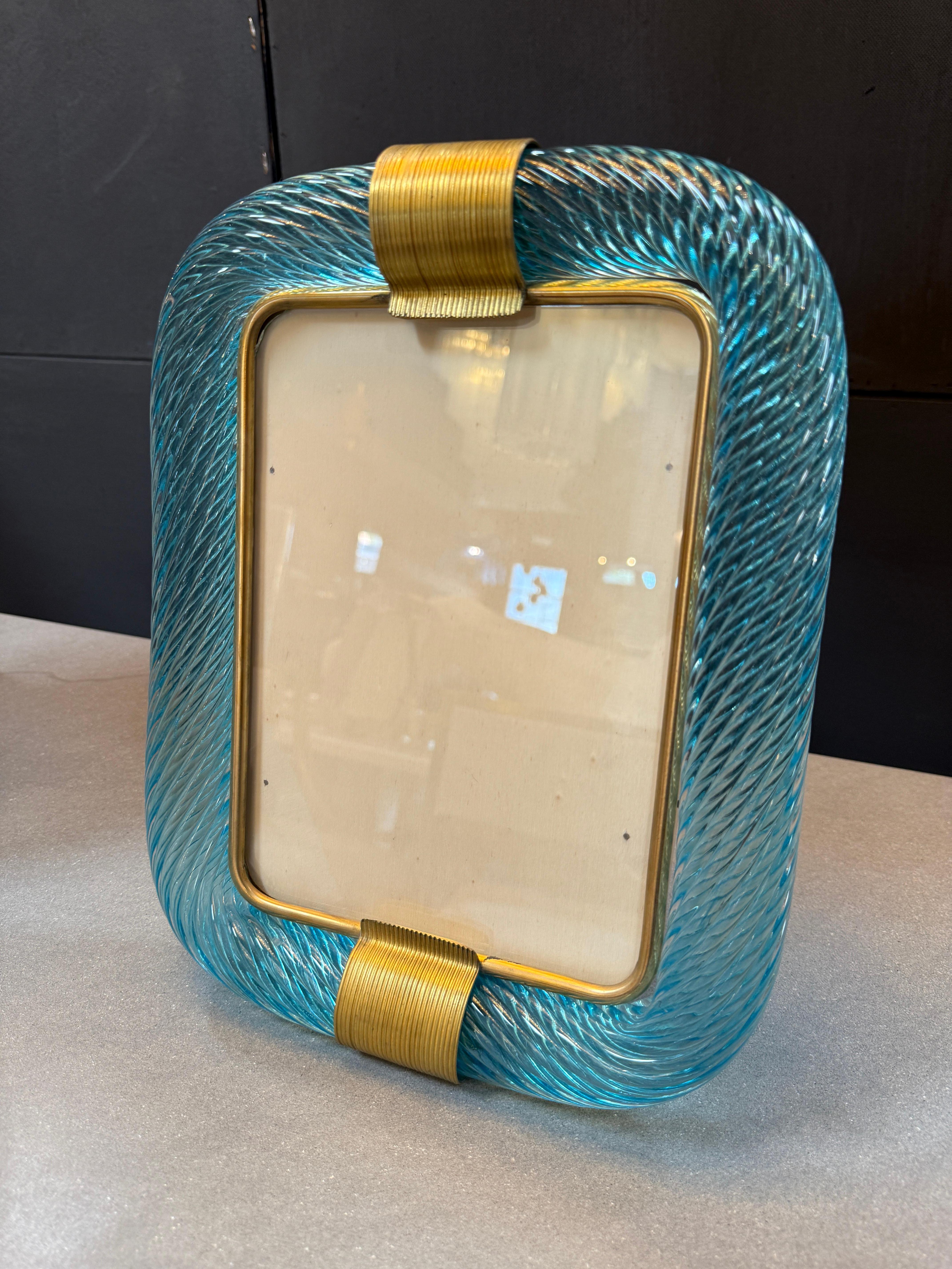 This is a striking vintage picture frame, crafted with a bold combination of twisted turquoise Murano glass and brass detailing. Its design reflects the luxurious craftsmanship and aesthetic flair of mid-century Italian decorative arts.

