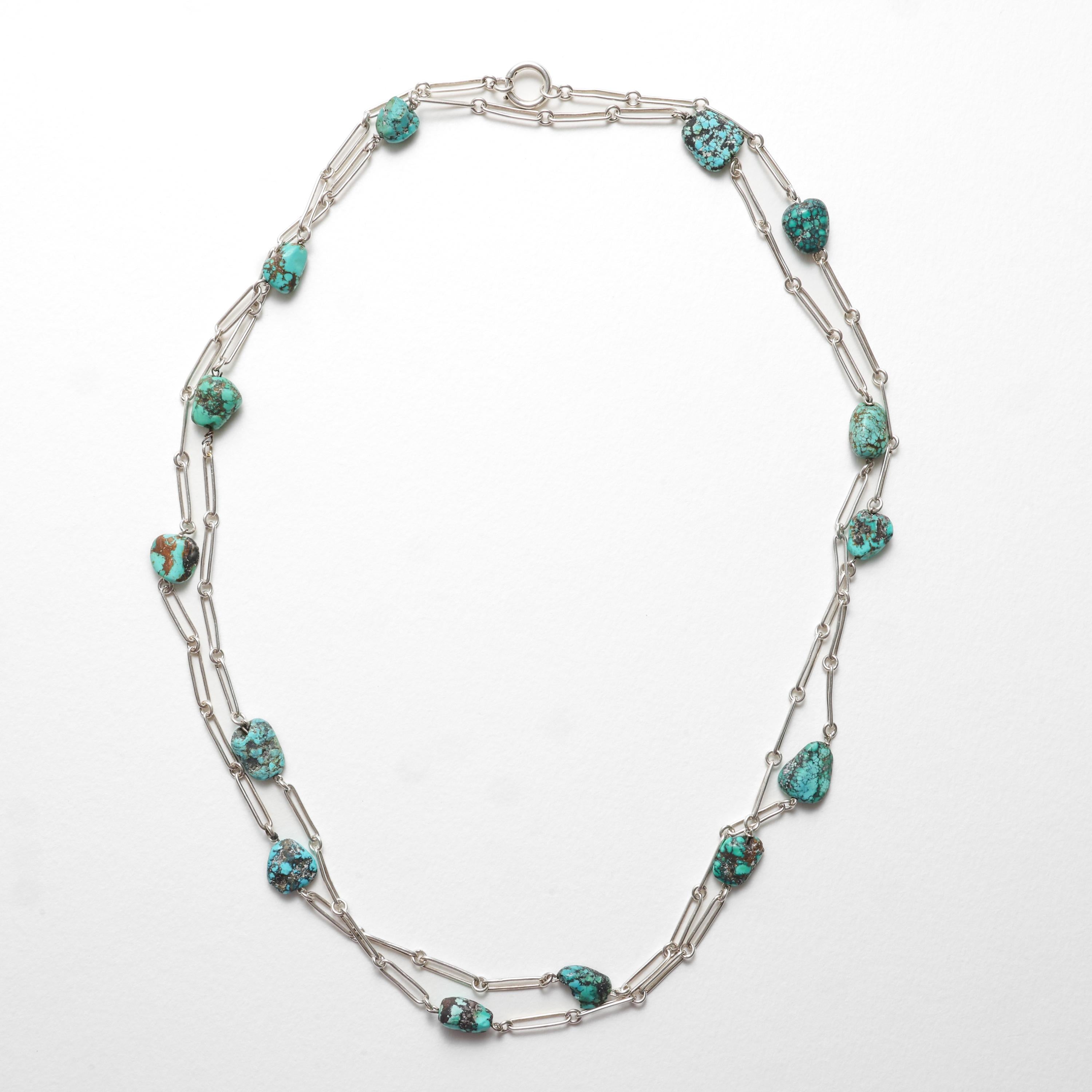 Questa collana in argento da 52 pollici con pepite di turchese è stata creata in stile Arts & Crafts, molto probabilmente negli anni '70.

Le maglie in argento a graffetta, larghe 3,73 mm, sono punteggiate dalle più belle e affascinanti pepite di