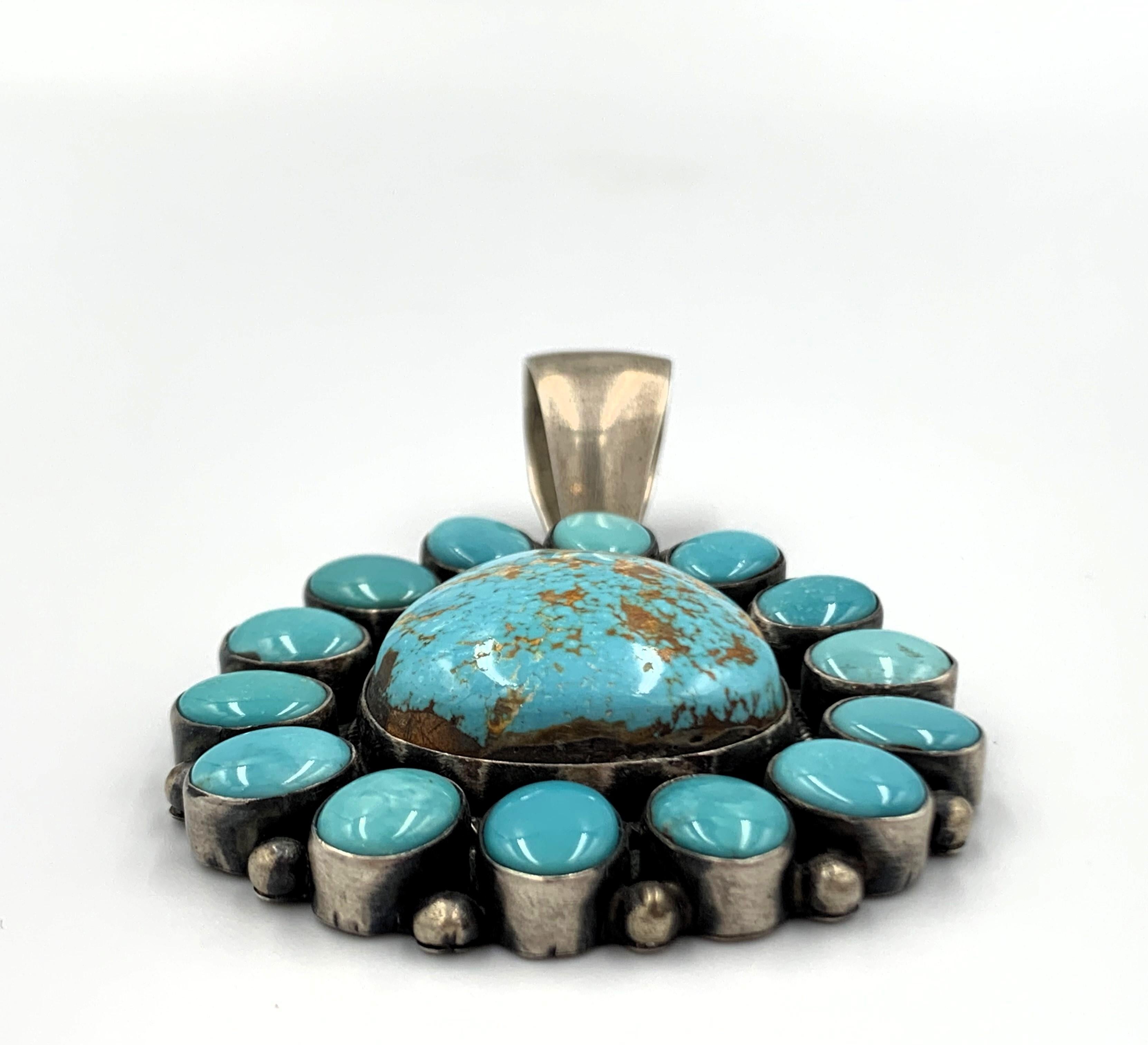 Sterling silver pendant by Navajo silversmith Bea (Betty) Tom. The 2” x 2” pendant with a 3/4” bale has 14 Carico Lake turquoise cabochons surrounding a 1” x 1 1/8 Carico Lake turquoise stone. Hallmarked  