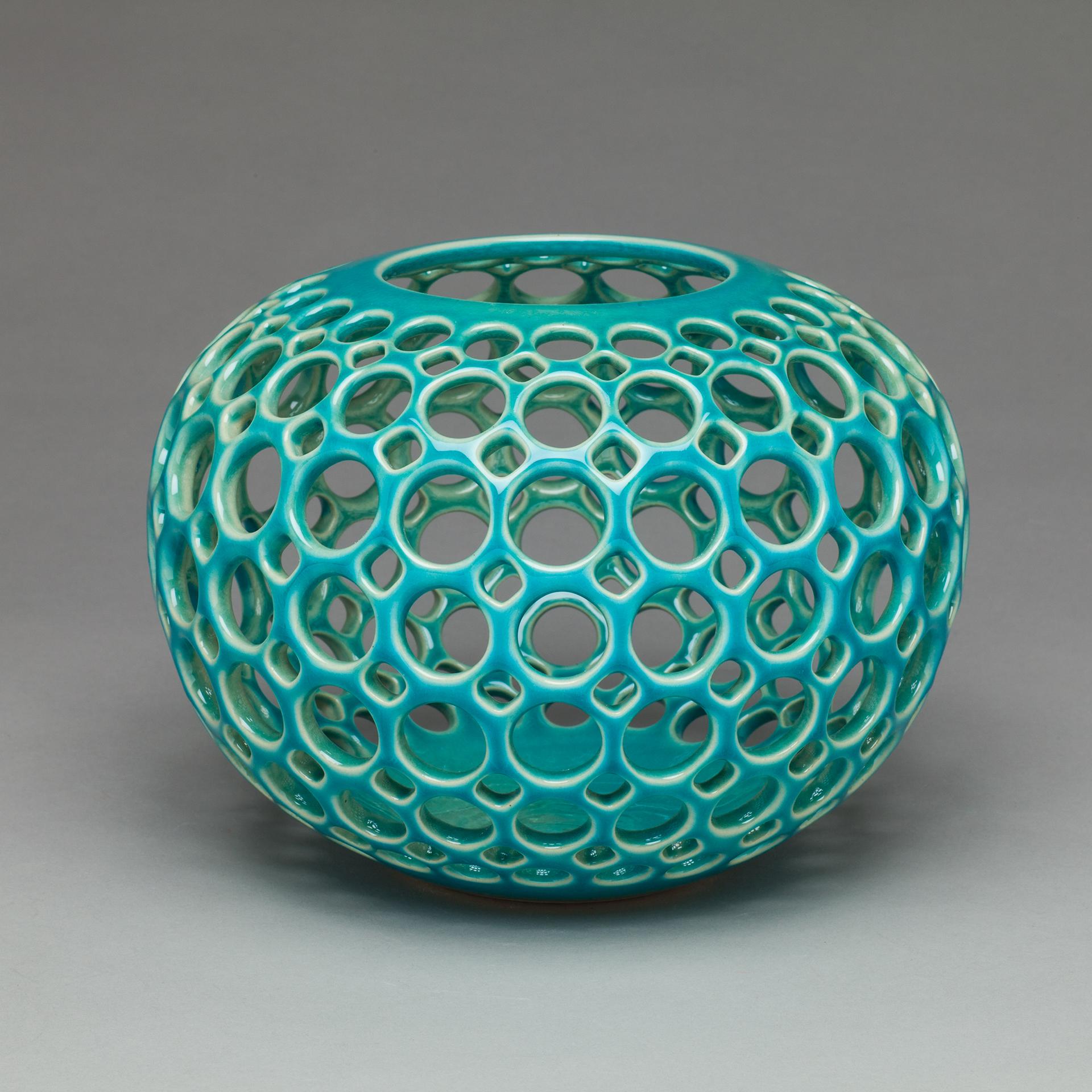 Inspired by Mid-Century Modern design, this piece is wheel thrown and hand pierced stoneware with a turquoise crackle glaze. Small holes are created when the clay is still wet and then each hole is painstakingly enlarged and smoothed when the clay