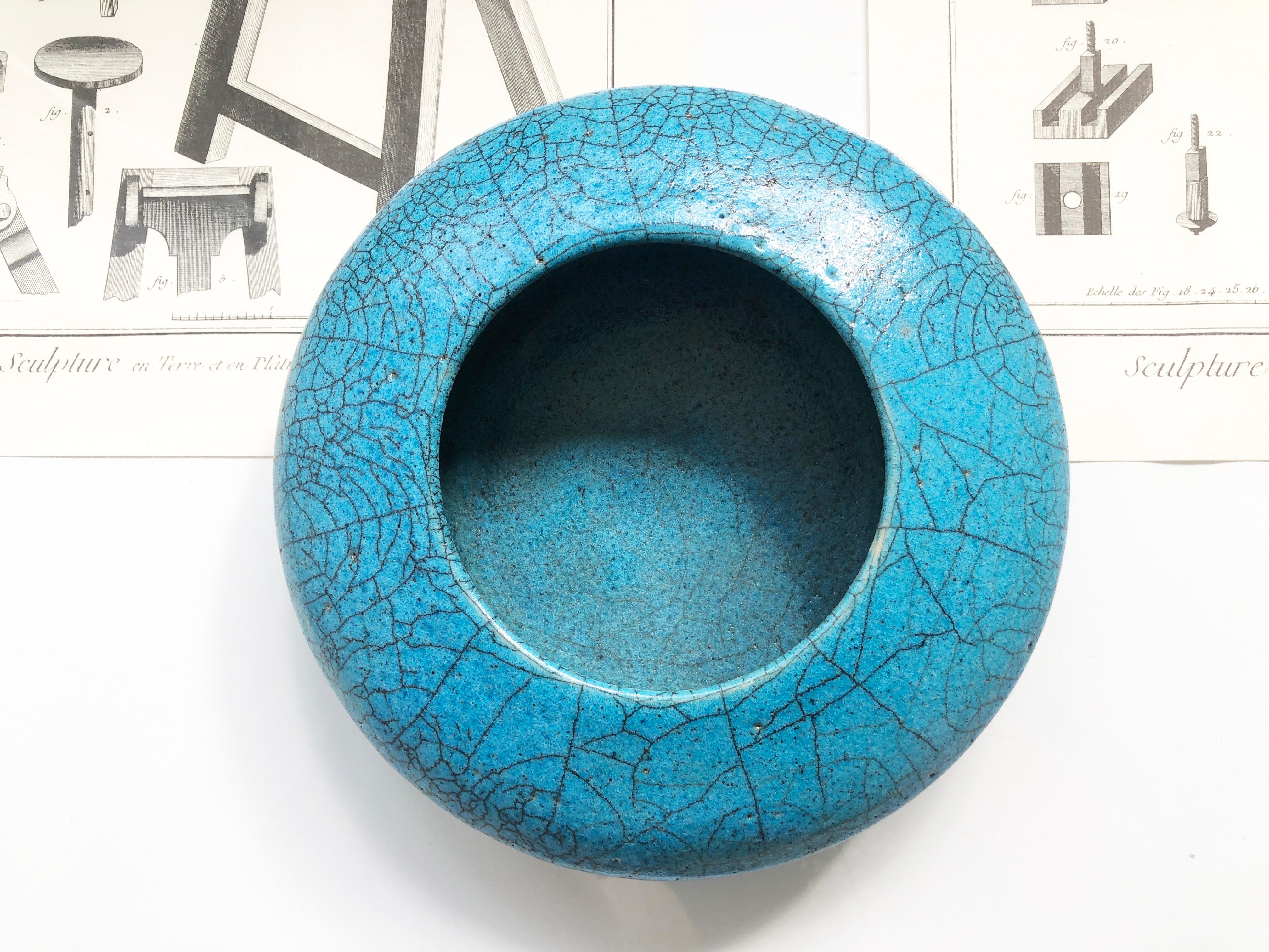 Ein wirklich ungewöhnliches Kunstwerk ist diese niedrige, scheibenförmige Schale oder Vase mit einer türkisfarbenen Raku-Glasur und fetten Lava-Andeutungen am Boden.
Der Keramiksockel zeigt das tiefe Holzkohleschwarz des Grundmaterials.
Die