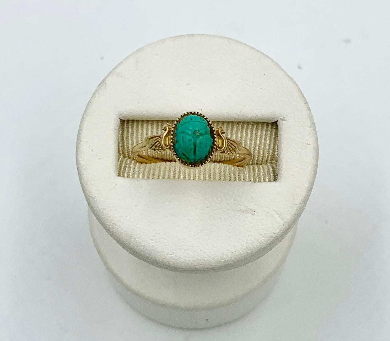A museum quality antique Egyptian Revival Scarab Phoenix masterpiece.  The ring has a central Scarab carved in Turquoise of great beauty.  The Scarab is set in a 14 Karat Gold beaded collet.  On either side of the Scarab are stunning renditions of a