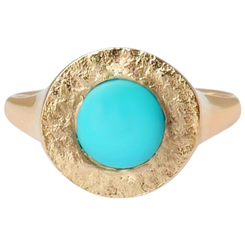 This textured signet ring crafted in solid 14-carat gold features a raised natural Arizona turquoise cabochon embedded in a shimmering texture.  The ring is finished with a high polish on the sides and band for a comfortable fit.  This ring is a UK