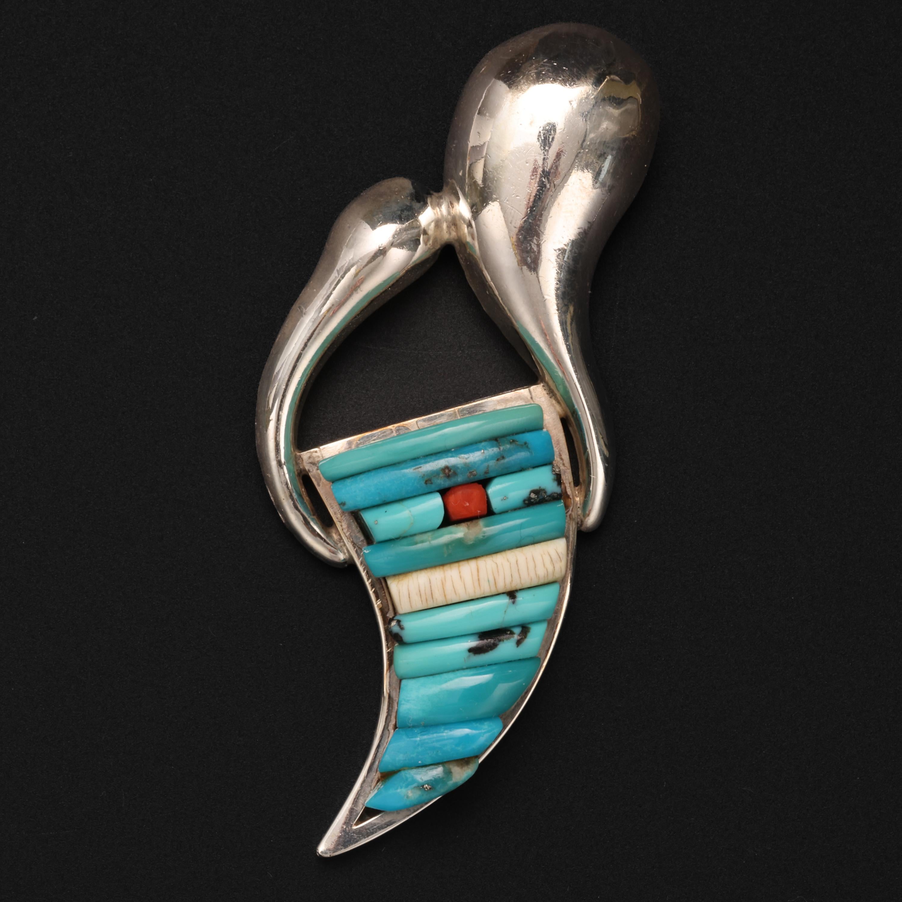 This signed, handmade pendant was created in sterling silver, turquoise, bone, and coral by noted Navajo artist, Pete Sierra. Sierra, who studied under Hopi artist Charles Loloma, has created his own highly sought-after style. 

This gorgeous and