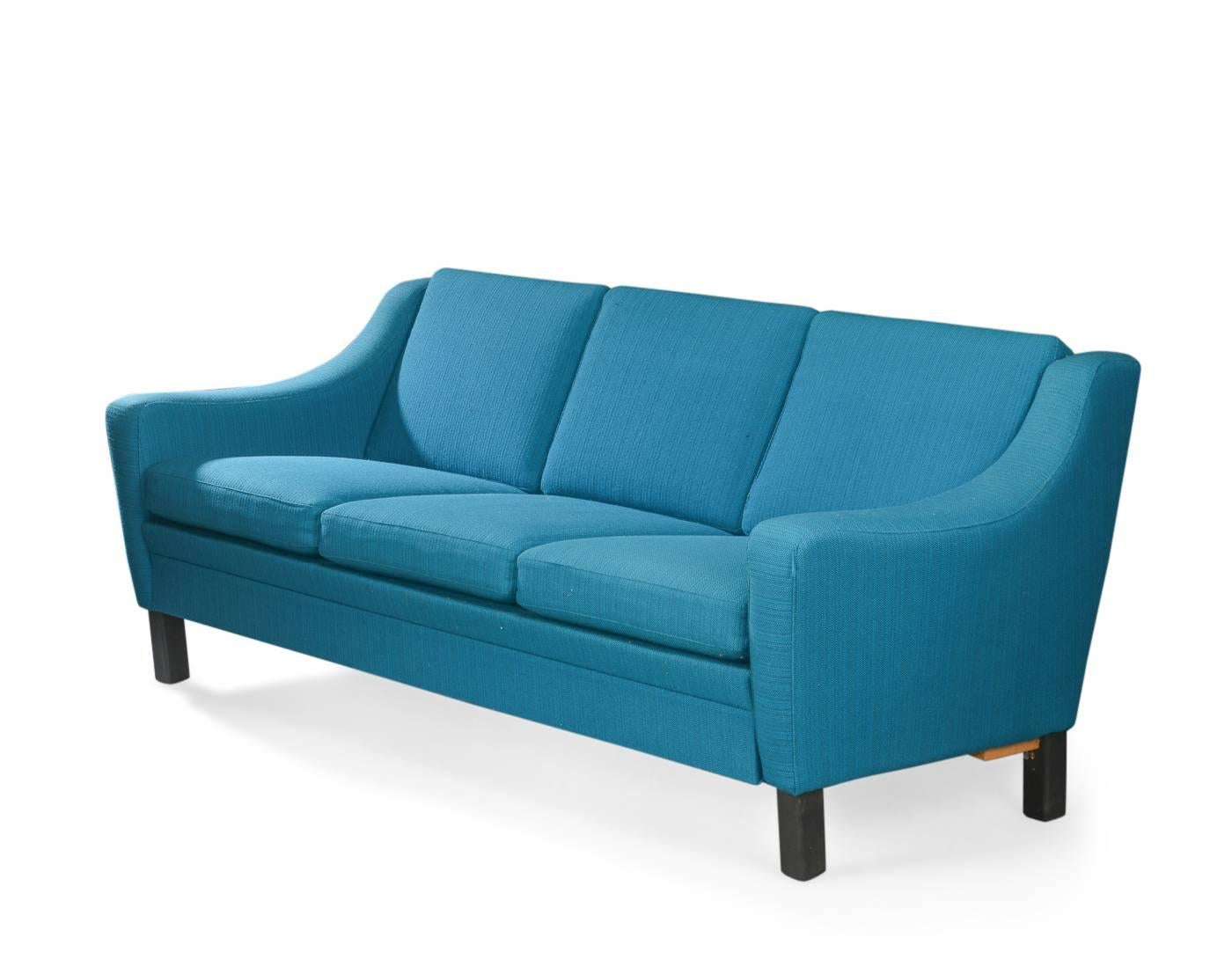 Upholstered sofas upholstered in turquoise wool, soft cushions and legs in black lacquered wood. 
Set consisting of a sofa measure: W. 210, H. 87, D. 79 cm, two small armchairs W. 92 cm
Sofa with repair on hind feet.