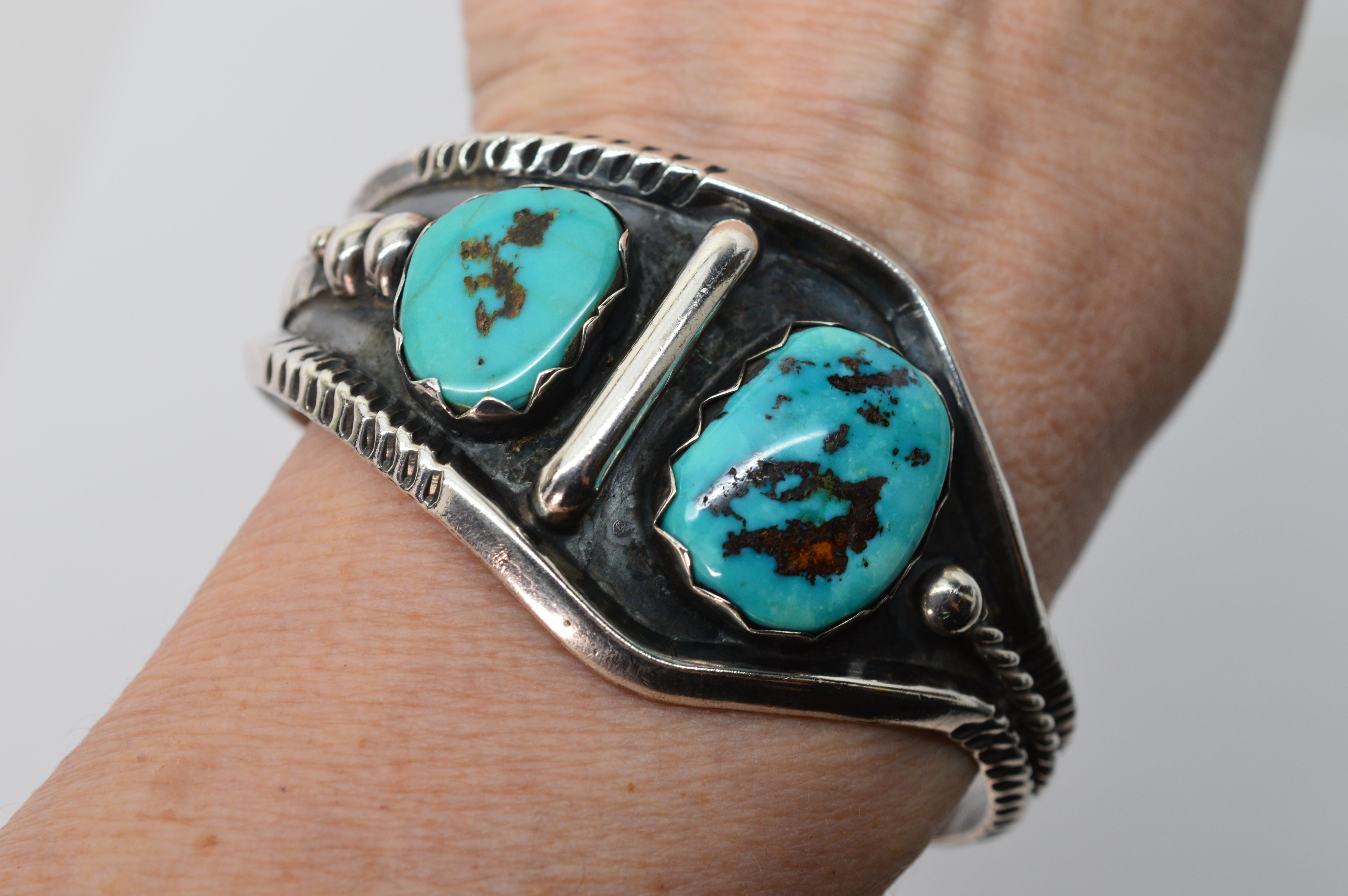 This dramatic Southwest style piece is defined by its asymmetrical shape and large bezel set turquoise stones. Blackened sterling further accentuates the natural beauty of the turquoise and the Navajo silversmith's artistry. This generously sized