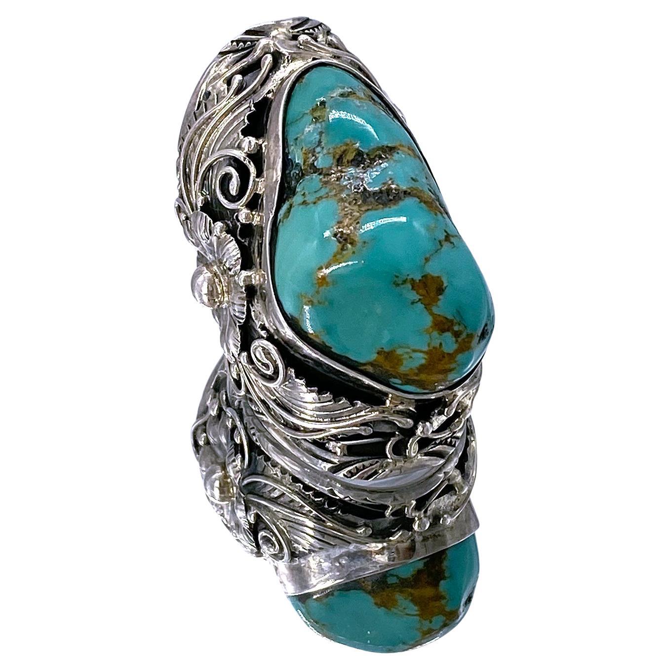 This is a large free form turquoise sterling statement ring. It has a 33 mm x 20 mm natural textured turquoise bezel set in a sterling silver adjustable ring with a richly detailed flower and leaves pattern.

Our vintage jewelry collection and