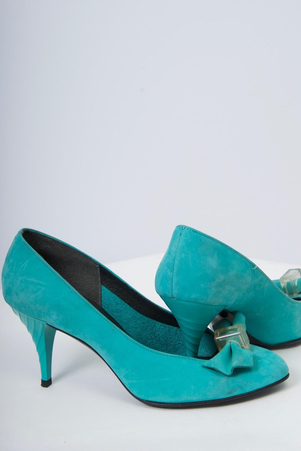 Turquoise suede pumps feature a bow held in middle by lucite element at the low vamp and a sculpted plastic heel. Approximate size 7.