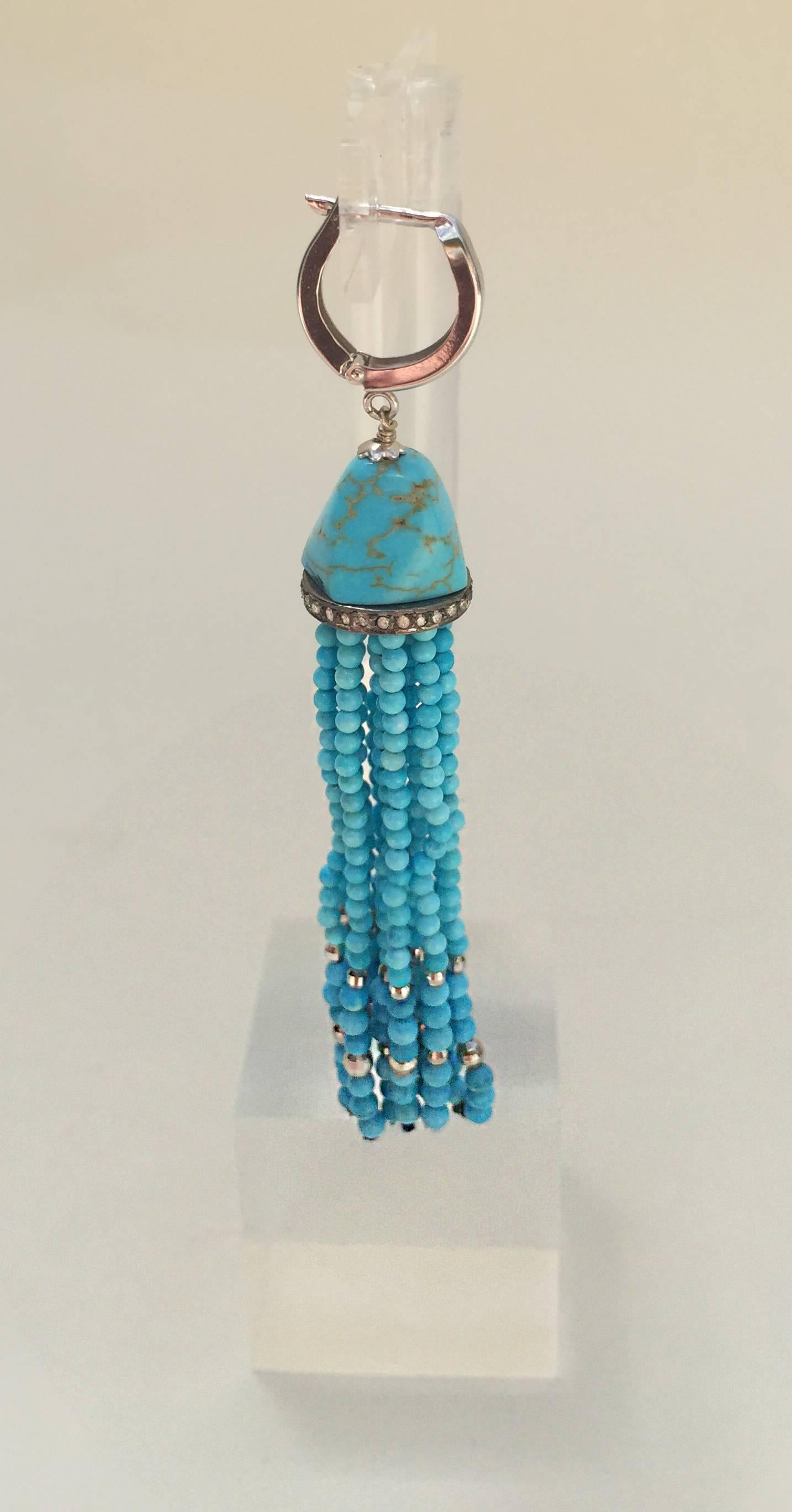These beautiful turquoise tassel earrings are accented with silver rhodium plated faceted beads. Bringing the strands together is a large turquoise bead and diamond encrusted silver roundel. Completing the look is 14 k white gold lever backs that