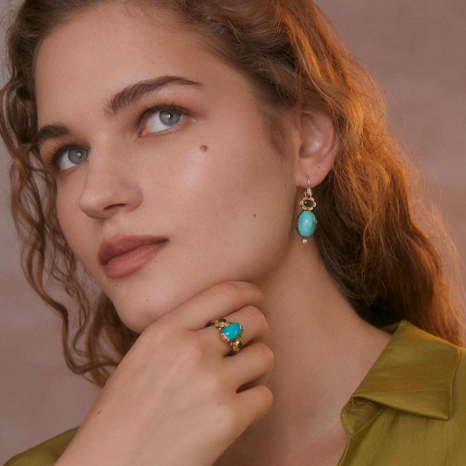 Uno squisito anello di tormalina turchese unico nel suo genere. L'anello presenta un turchese centrale affiancato da due tormaline cabochon verdi. È realizzato in oro 18 carati e argento ossidato. Presenta motivi incisi a mano in oro 18 carati con