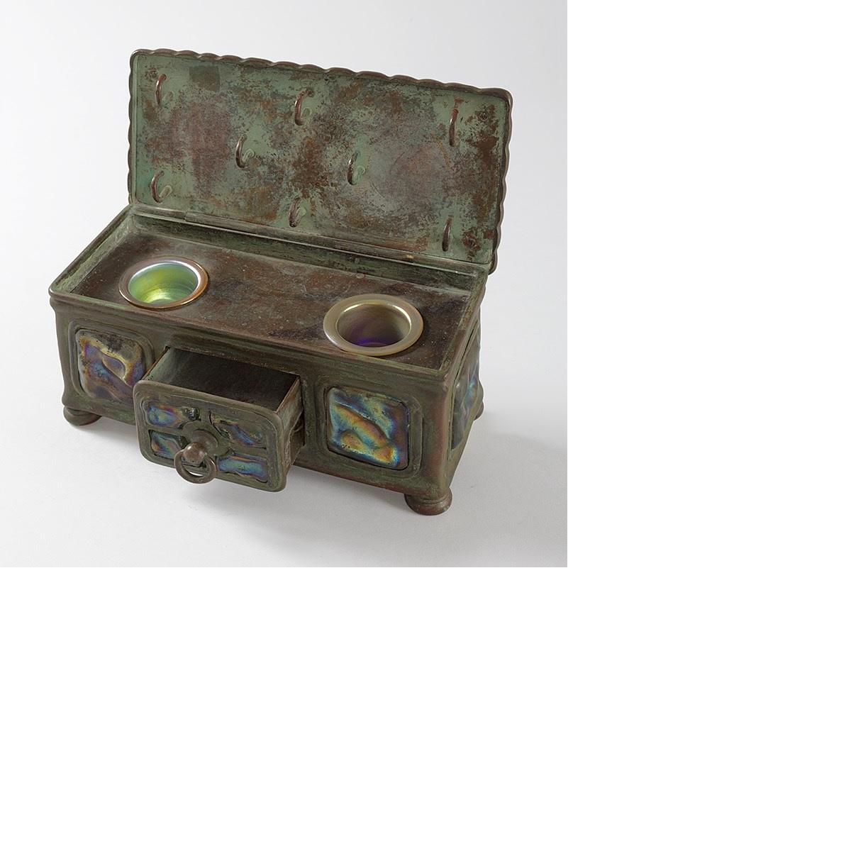 A Tiffany Studios New York Art Nouveau patinated bronze and turtleback tile inkstand by Tiffany Studios New York. The top and sides of the inkstand are decorated with panels of multi-colored turtleback tiles. The interior holds two inkpots; the