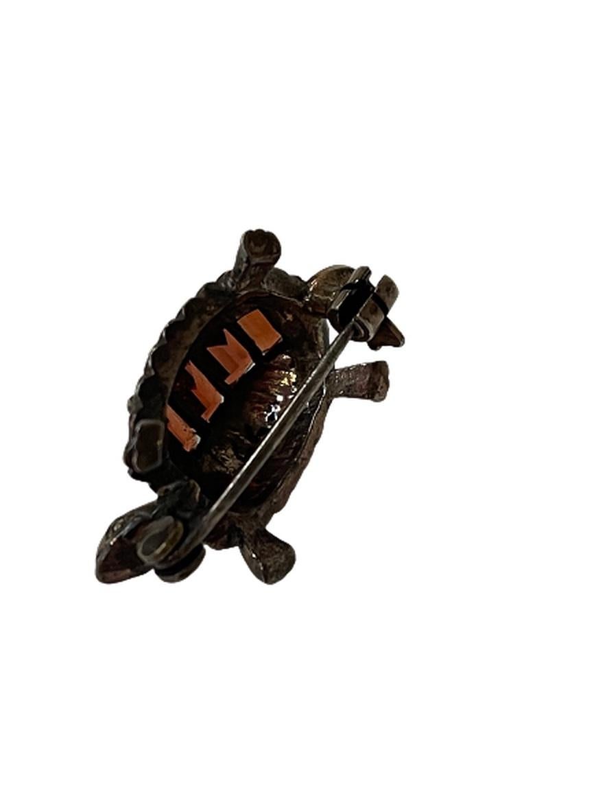 This is a sterling silver turtle brooch with marcasites and amethyst-type stones. It has a locking pin on the back to keep the turtle secure. The amethyst-type stone runs up the center of the turtle's back, while the marcasites decorate its
