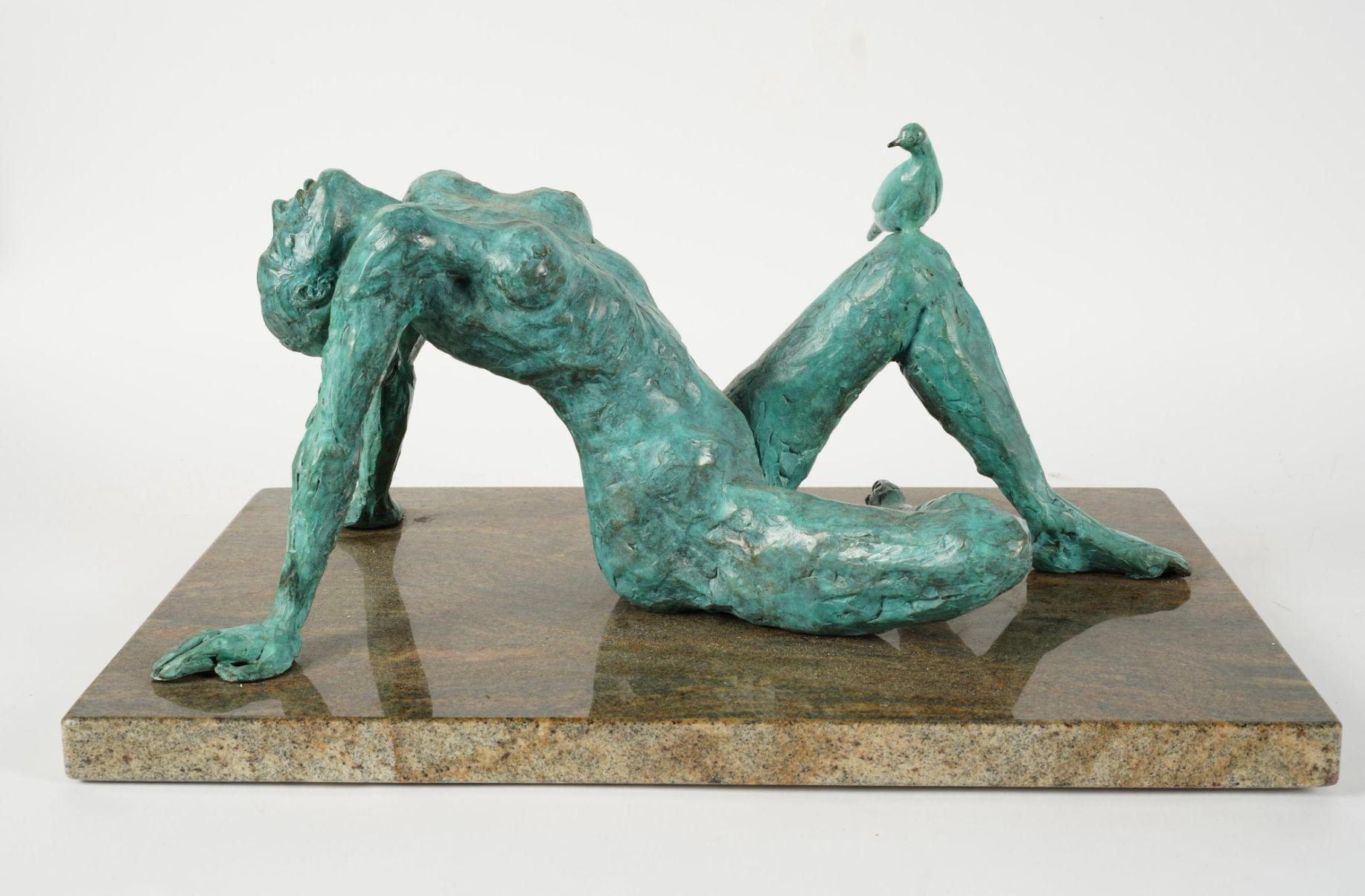 Una seducente scultura in bronzo patinato di una donna nuda adagiata su un basamento in pietra; la donna è rivolta verso il cielo ed è accompagnata da una piccola colomba in piedi sulla sua gamba. Questo bellissimo pezzo è realizzato da Richards