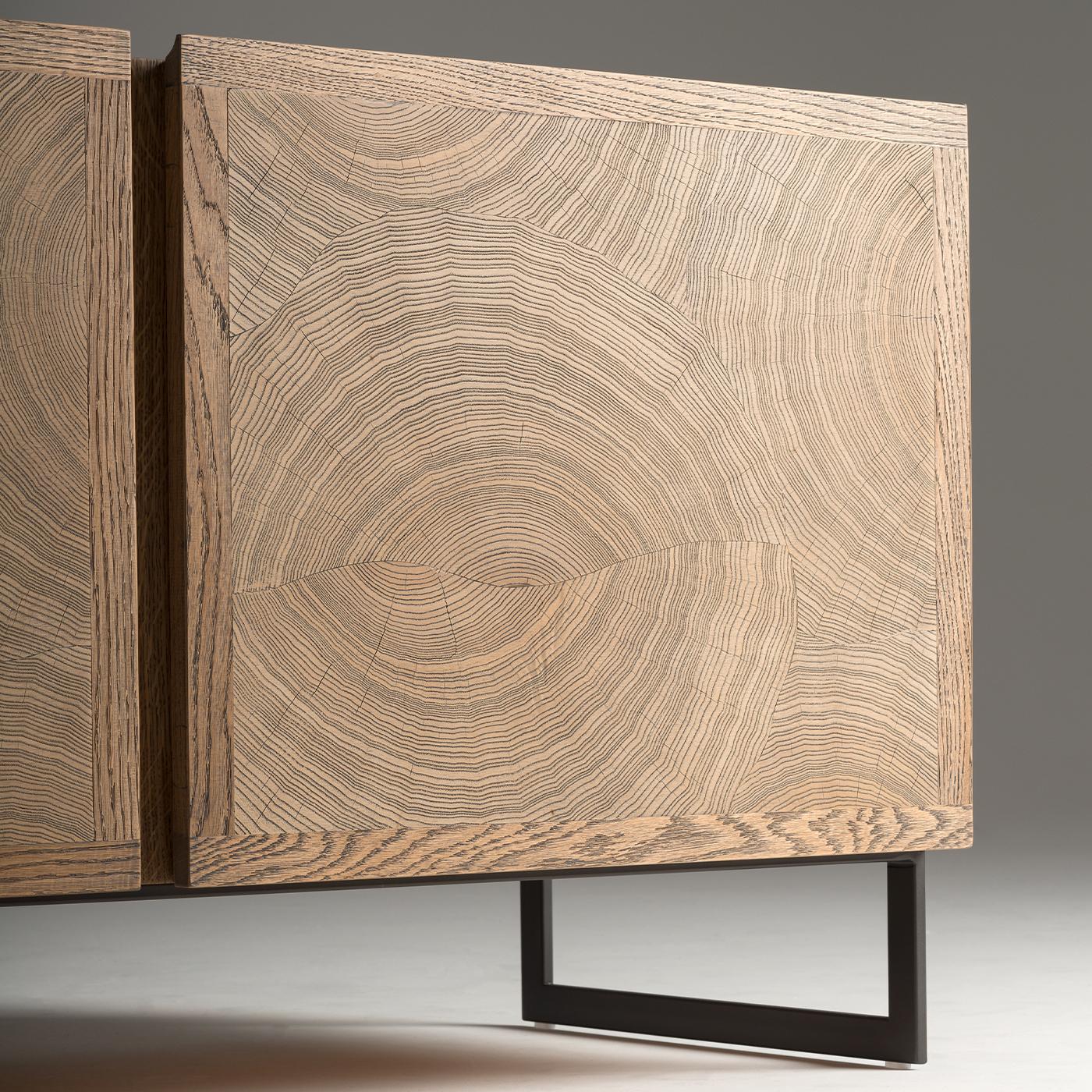 Tv holder with a linear profile, with a natural and sober character but at the same time with a significant impact thanks to the particular and innovative veneer. Wood is the real protagonist of this object: the decorative motif on the doors is made