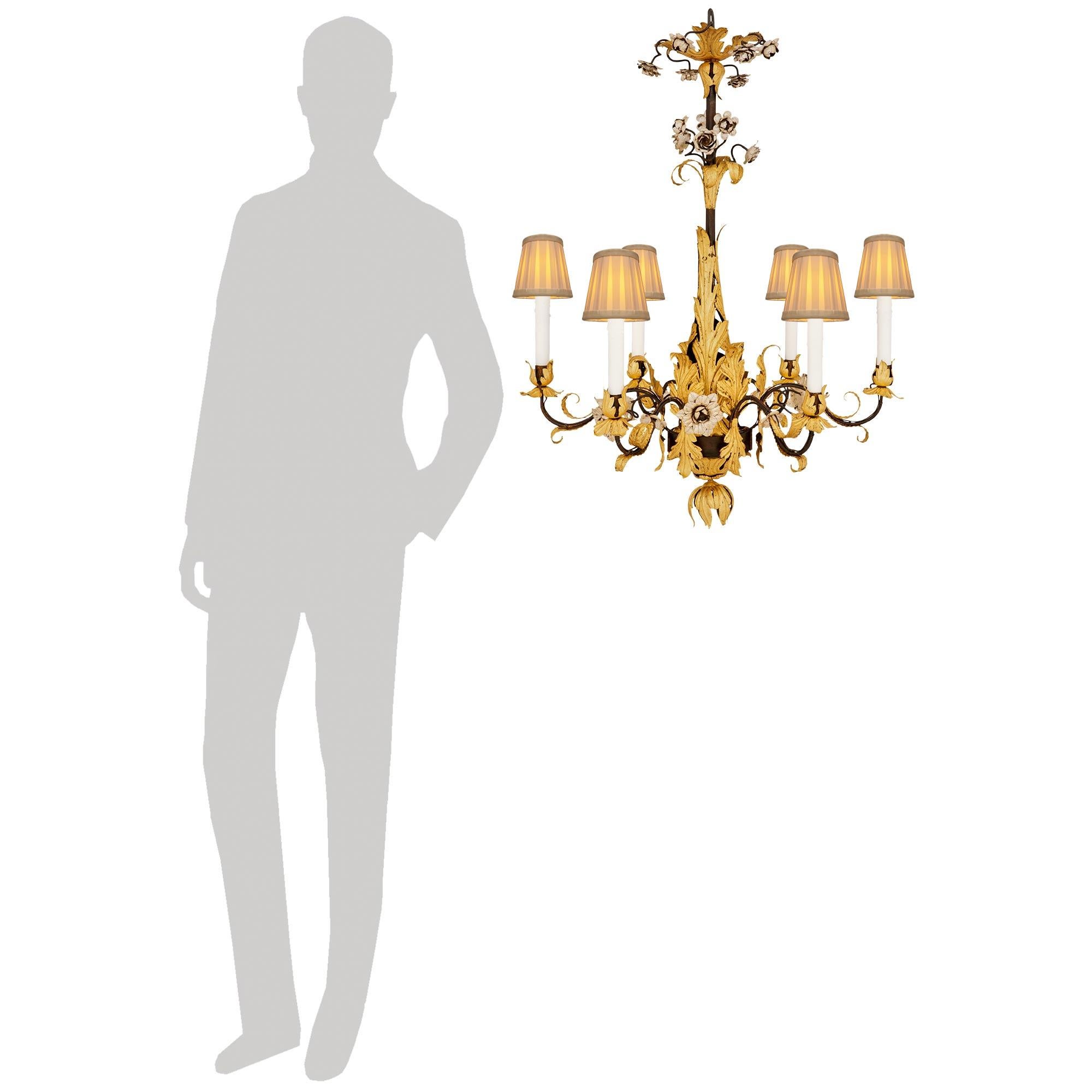 Un elegante e decoratissimo lampadario toscano del XVIII secolo in ferro patinato, dorato e in foglia d'argento. Questo lampadario unico nel suo genere è centrato in basso da un terminale a foglia rovesciata sotto i sei bracci a voluta. Una fascia