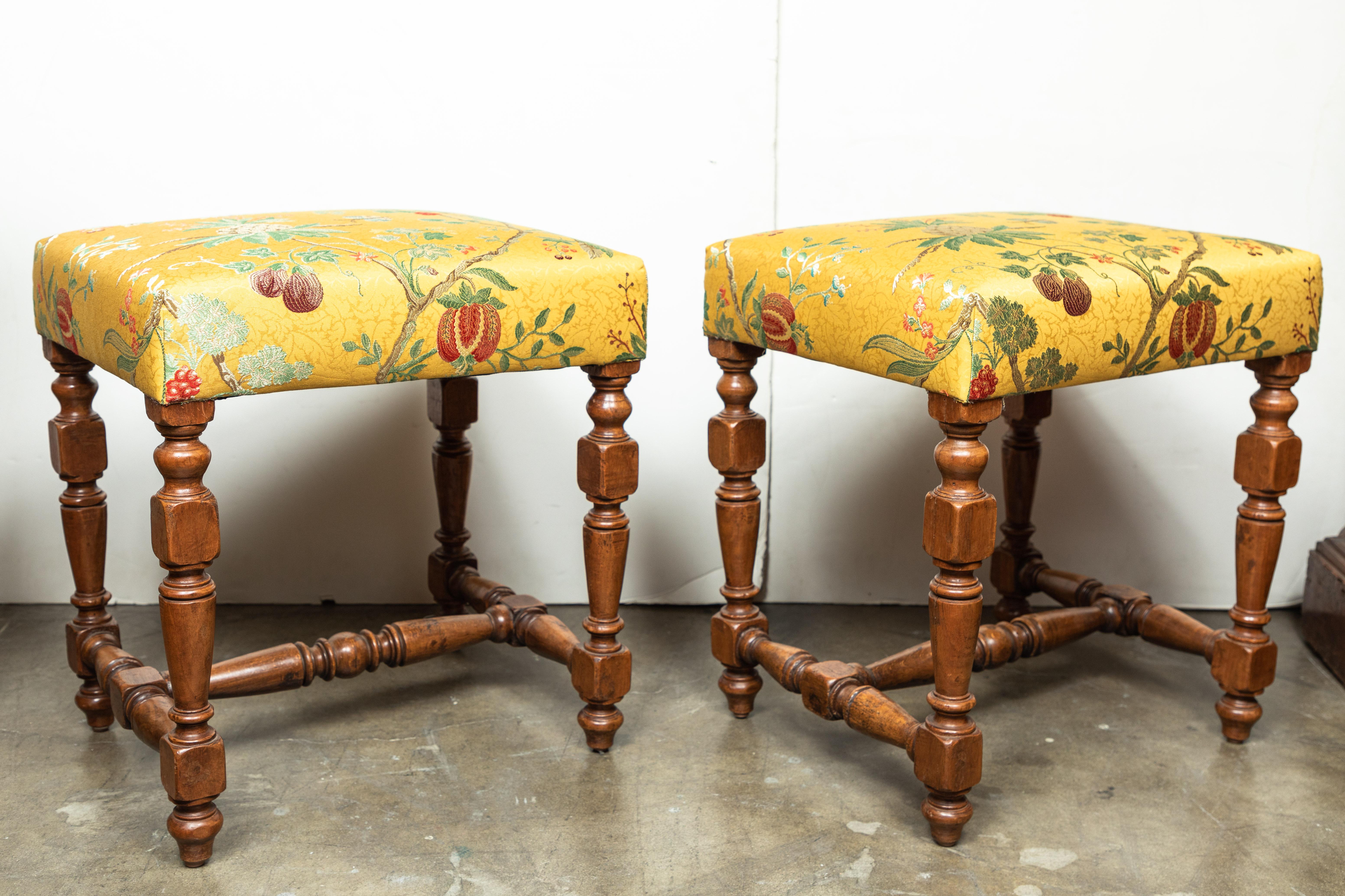 A pair of richly carved, vintage, Italian, solid walnut benches with turned stretchers. Newly upholstered in timeless, 18th century style, Scalamandre, 