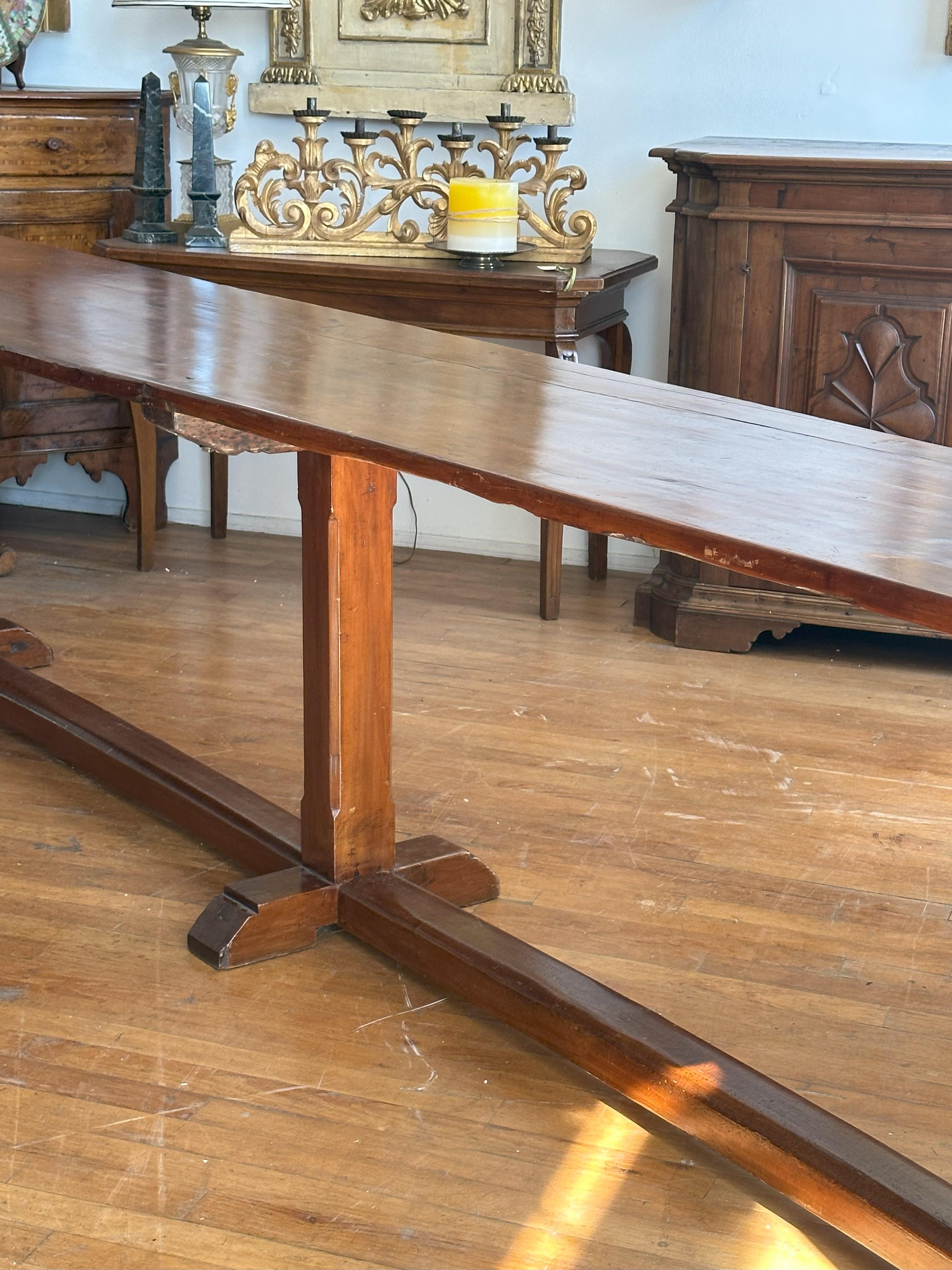 Tablero rectangular de un solo tablón elevado sobre tres soportes achaflanados unidos por camillas y terminados en pies extendidos y abocinados. 