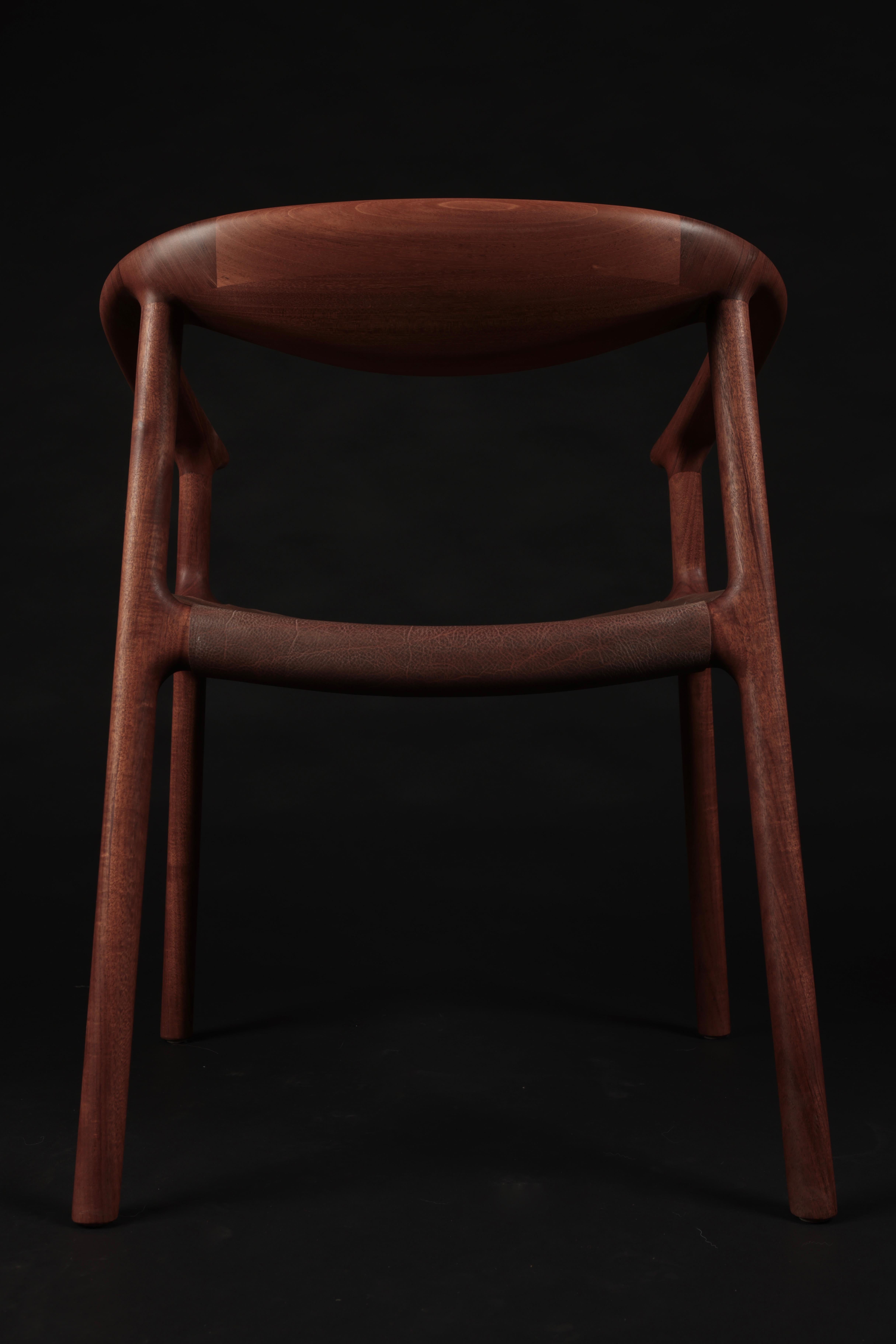 Tusk sling dining chair by Möbius Objects - hand-sculpted here in solid Honduran Mahogany.  Raked legs offer a unique 'wind-swept' silhouette. The veg-tan leather sling seat is ergonomically wrapped with contact points padded in high-density