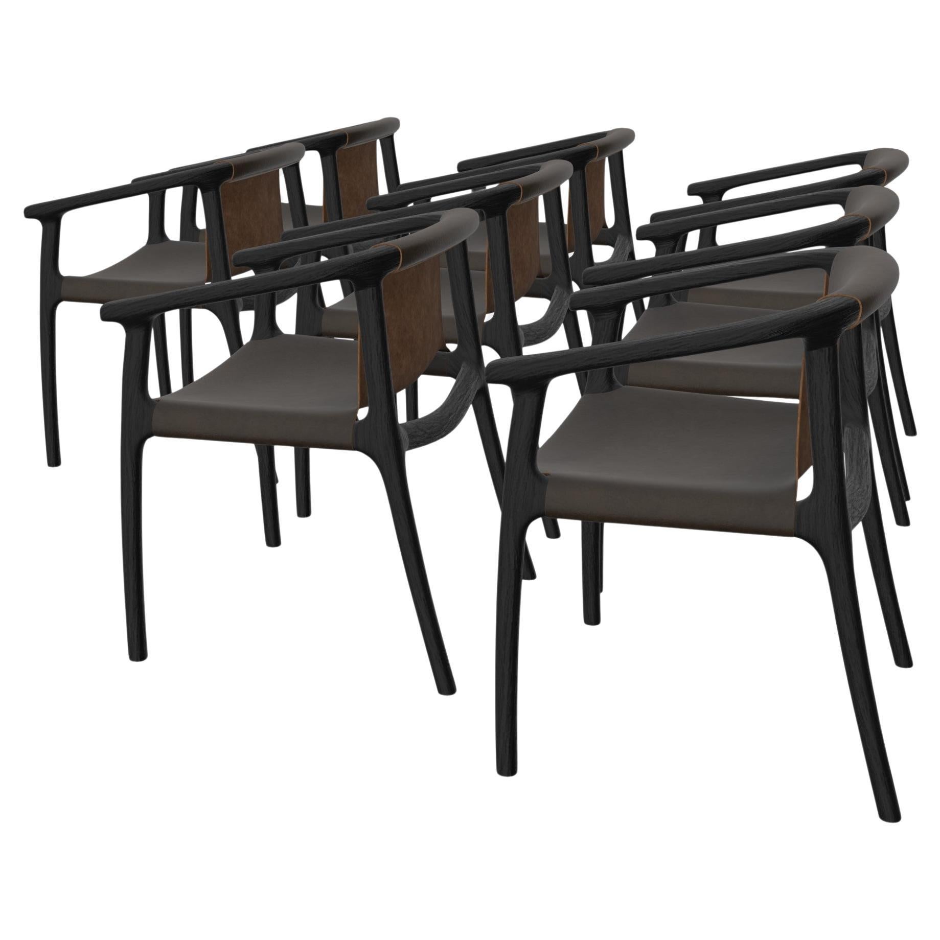 Tusk sling dining chair by Möbius Objects - hand-sculpted in solid American Ash in a black stain. Raked legs offer a unique 'wind-swept' silhouette. The veg-tan leather sling is ergonomically wrapped with contact points padded in high-density