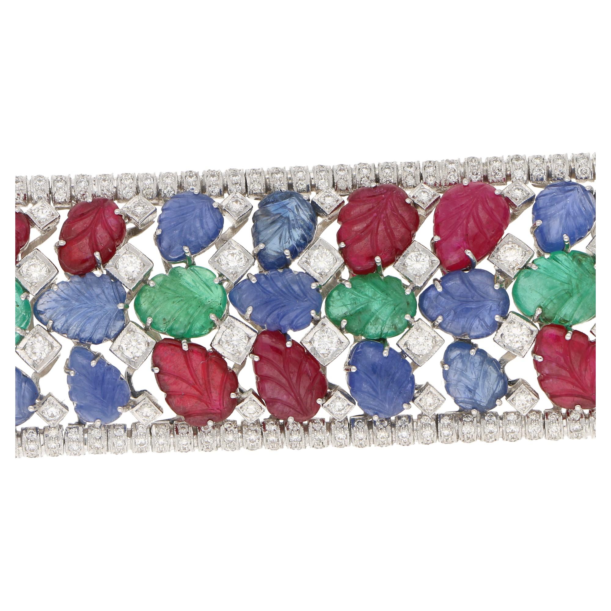 Carved Ruby, Emerald, Sapphire: 112.39 Carats
Brilliant Cut Diamonds: 7.13 Carats
G/H Color
SI Clarity 
18 Karat White Gold 
18.5cm long and 3cm wide

An elegant multi-gem set bracelet of contemporary make in the style of the Art Deco era, in