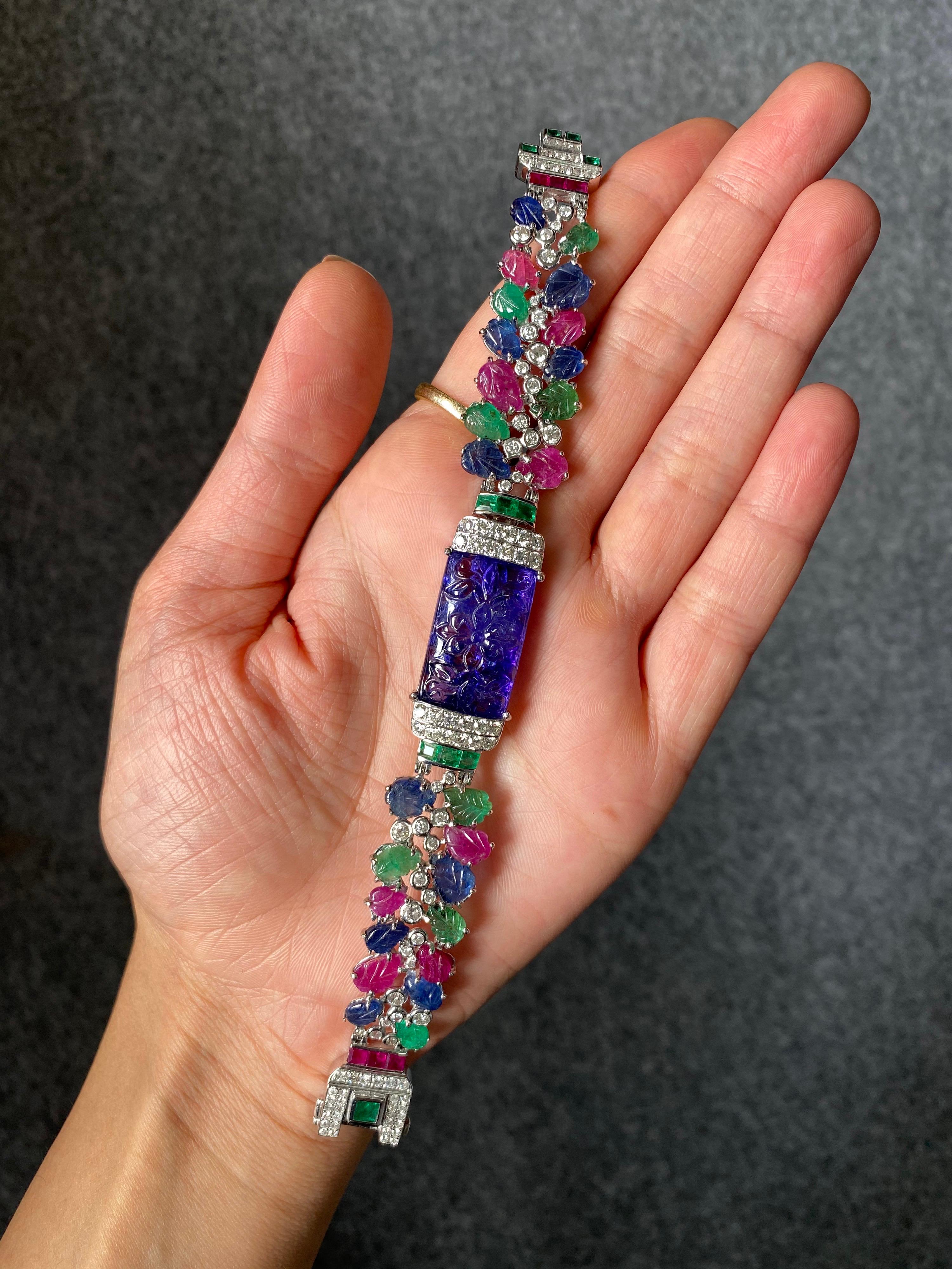 A lovely, art - deco inspired multi-colored bracelet, using natural (untreated/not dyed) carved Colombian Emeralds, Burmese Sapphire and Burmese Rubies and carved centre-stone Tanzanite - all set in 18K solid White Gold with Diamonds. The length of