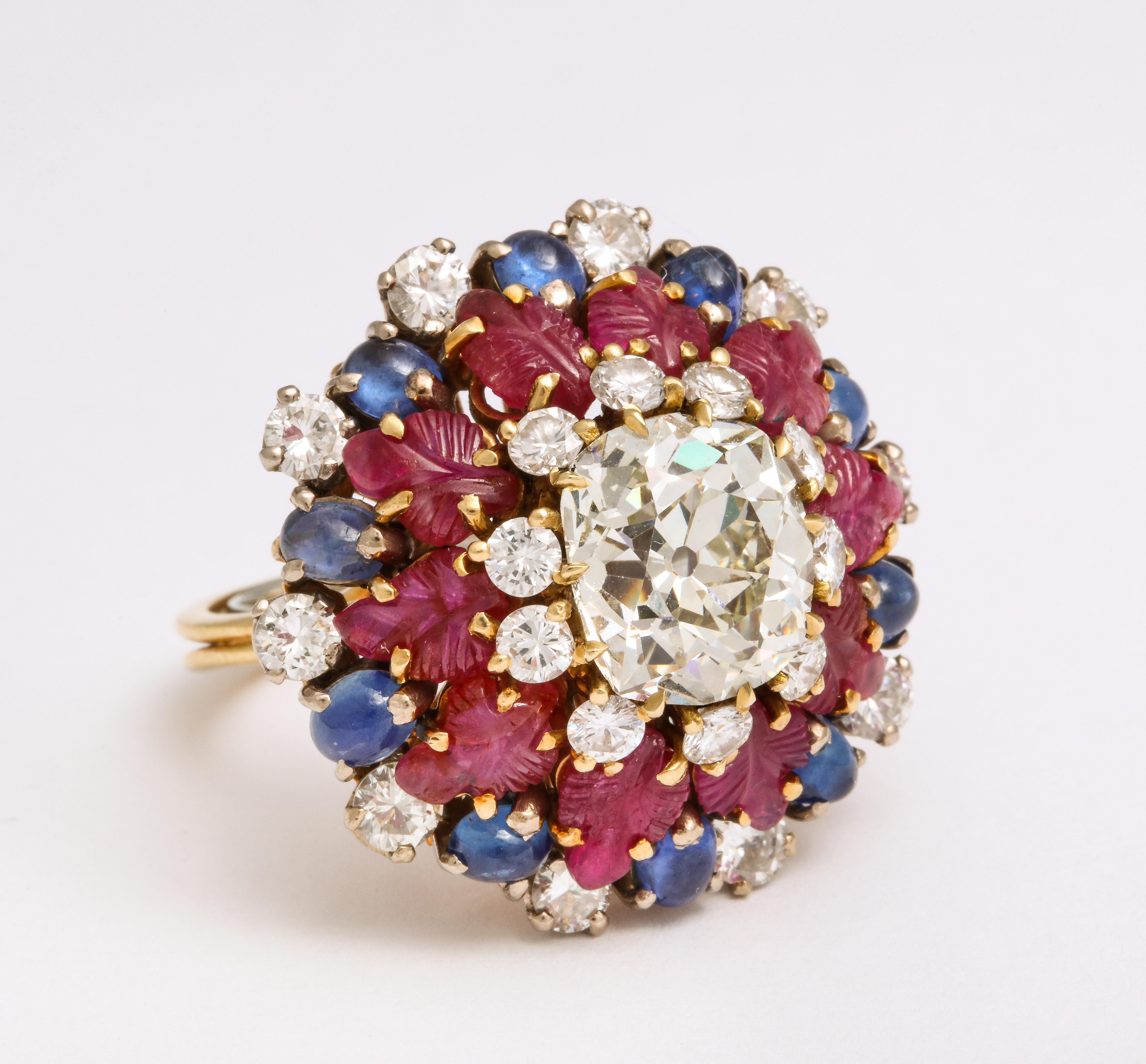 A Tutti Frutti Ruby Sapphire Diamond Gold Cocktail Ring circa 1950, with old mine cushion cut diamonds, ruby leaves and oval cabochon sapphires in yellow gold, measuring an impressive 1 1/5 inches wide and 1 inch high.

Material:
Yellow
