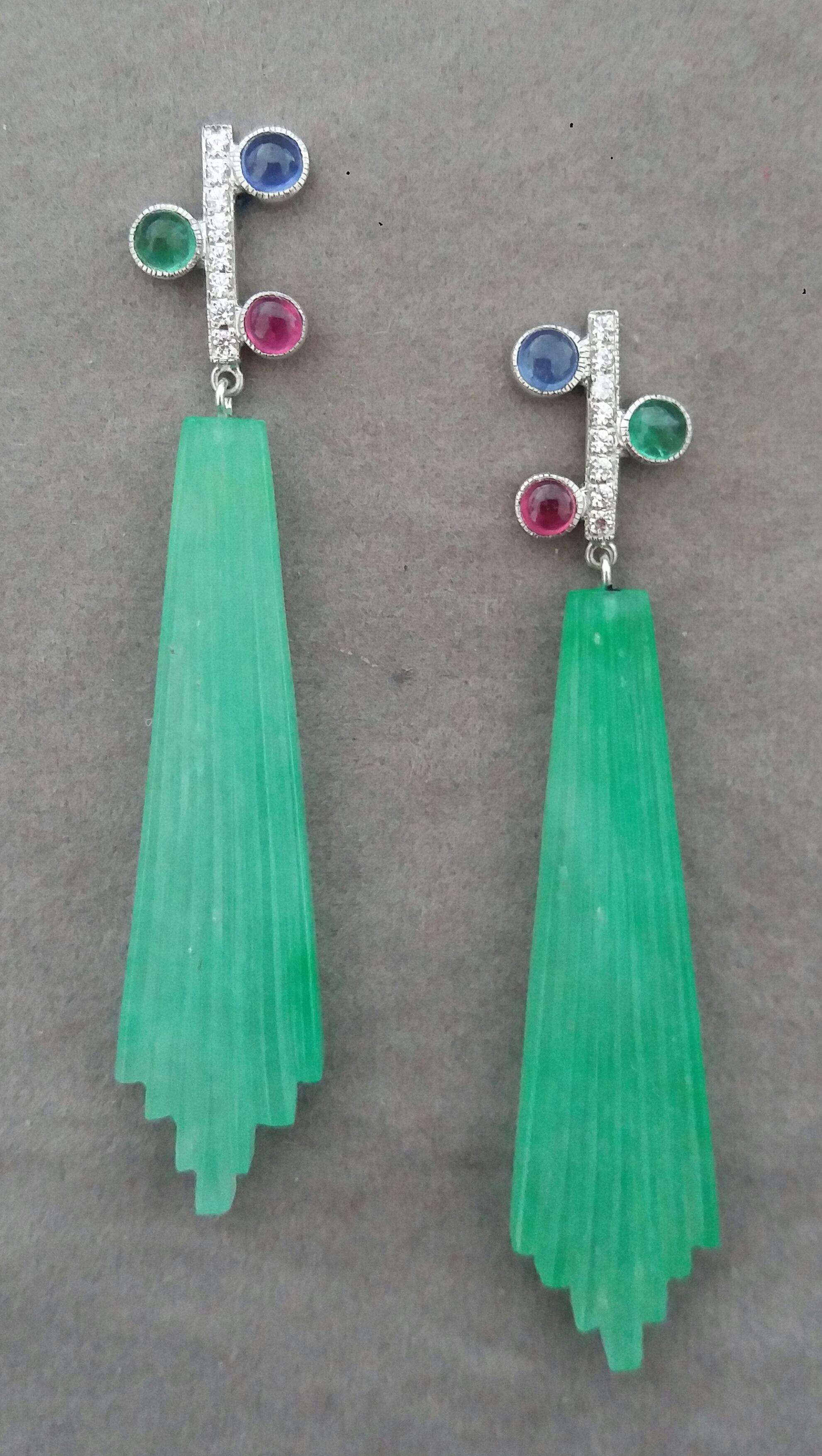 In these classic Tutti Frutti Style earrings the tops are 2 White Gold and  Diamonds Bars, 16 full brilliant cut diamonds ,and 3 pairs of  Rubies ,Emeralds and Blue Sapphires round cabs,in the lower parts we have 2 Engraved Jade  Drops measuring 14