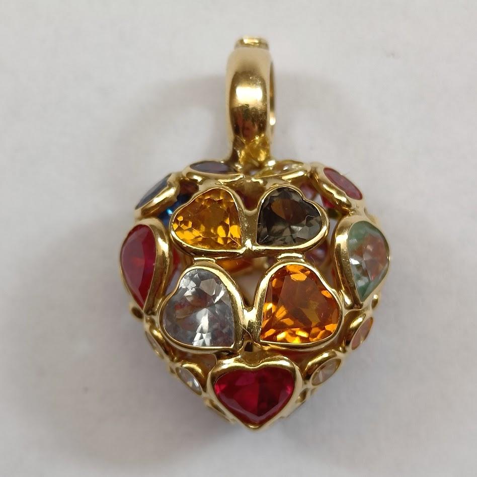 Un pendente a forma di cuore in oro giallo 18 carati con gemme sintetiche multicolori, alcune a forma di cuore, altre rotonde. Timbro 750 e marchio di fabbrica italiano.
Condizioni perfette.

Dimensioni 3 x 1,8 cm (circa)
Peso 6.86 grammi