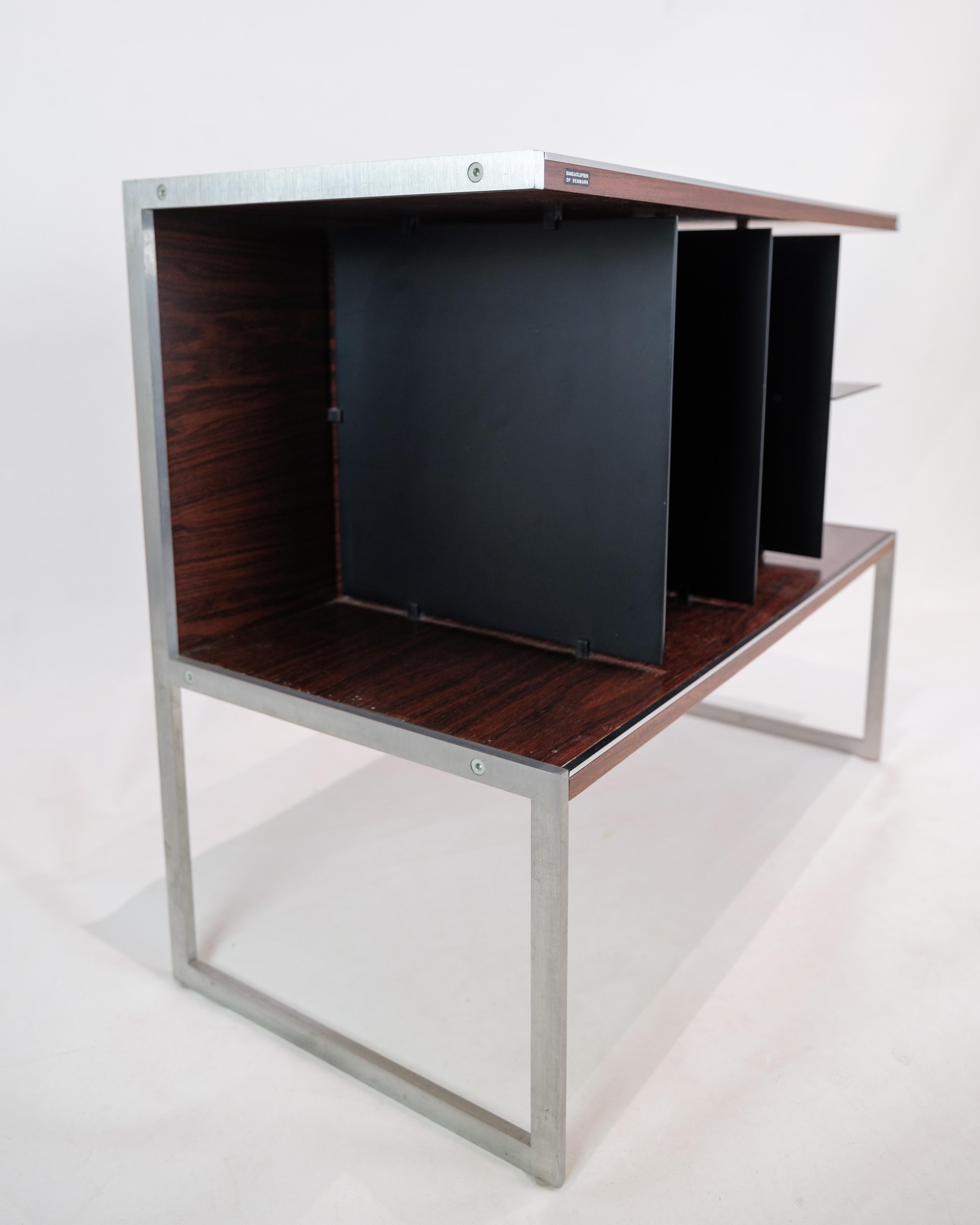 Ce meuble TV ou table d'appoint, conçu par Jacob Jensen en collaboration avec Bang & Olufsen, est un splendide exemple de l'esthétique moderne et de la fonctionnalité des années 1970. Fabriqué en bois de rose et en aluminium, ce meuble dégage un