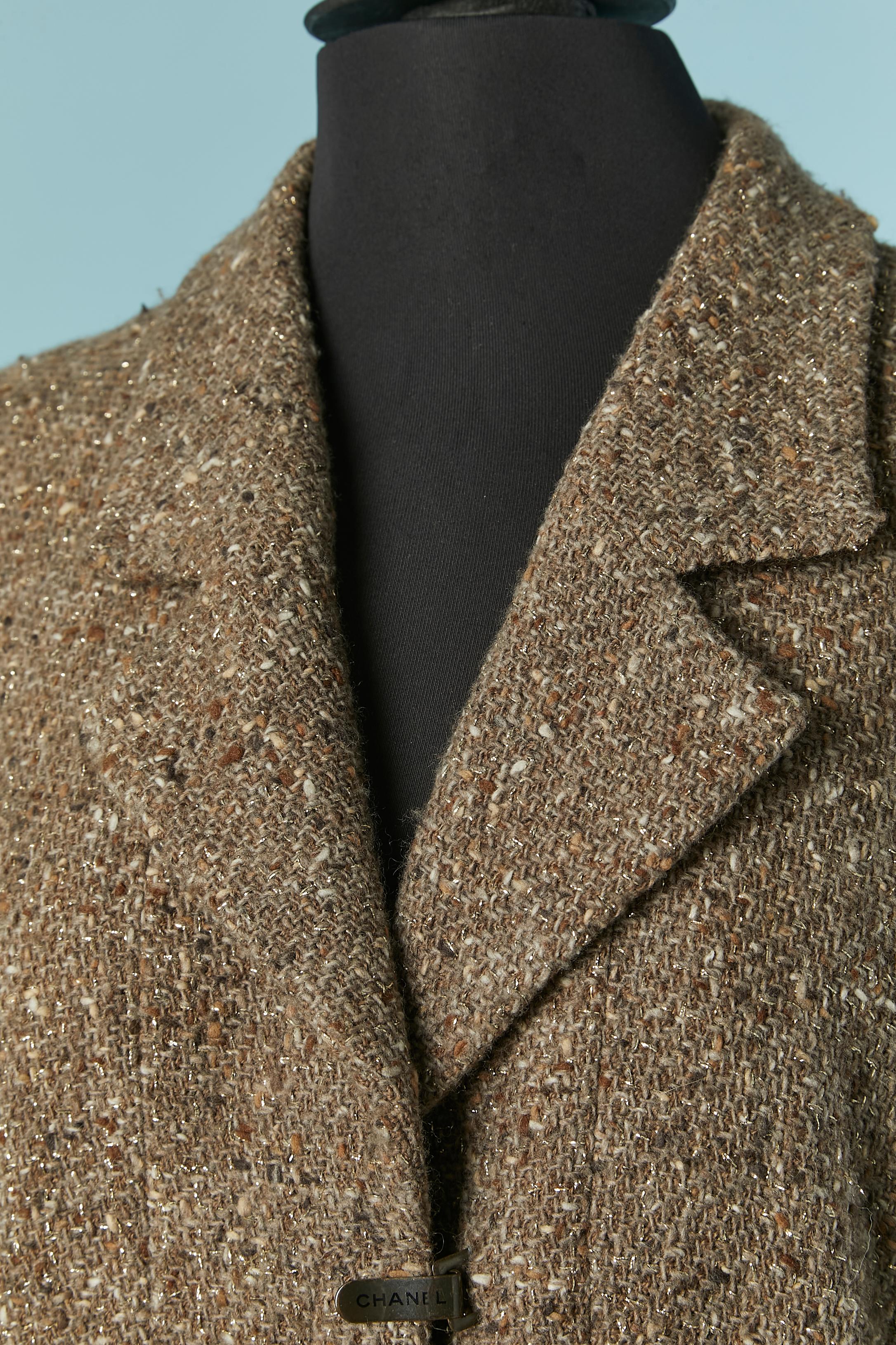 Giacca monopetto in tweed  con chiusura a scatto con marchio sul centro della parte anteriore.
Composizione del tessuto principale: 87% lana, 13% nylon. Fodera in seta con marchio. 
Catena all'interno della giacca sul bordo inferiore. Manica raglan.