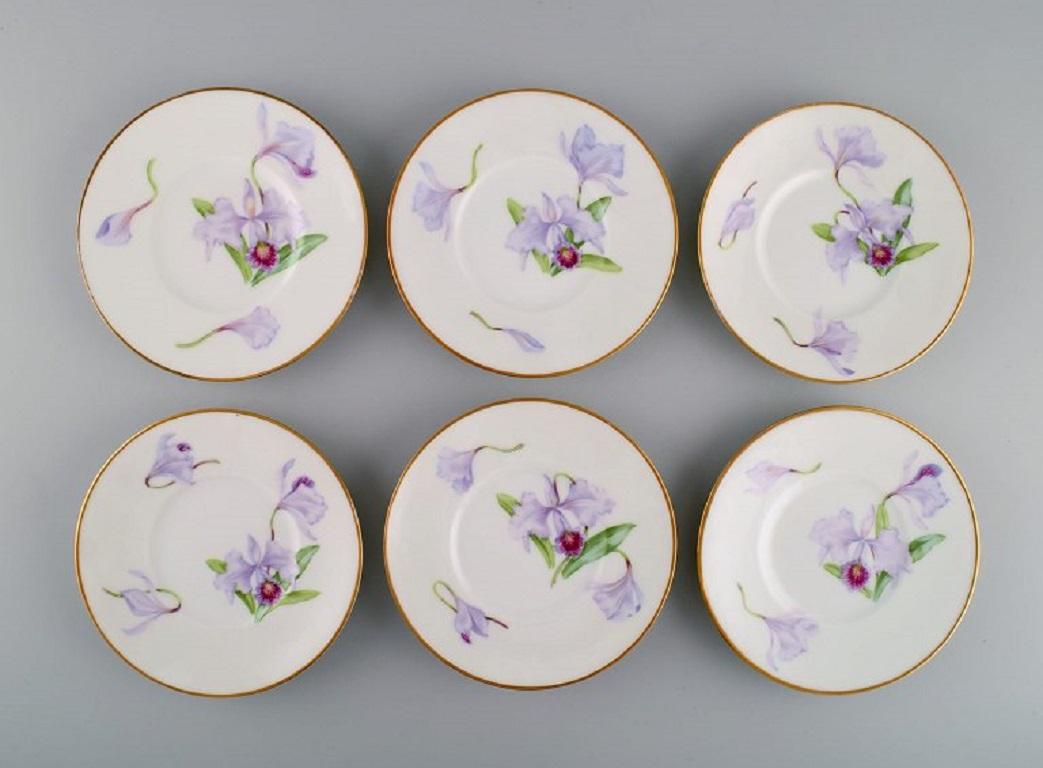 Douze assiettes anciennes et uniques en porcelaine de Royal Copenhagen avec des fleurs d'iris violettes peintes à la main. 
Numéro de modèle 72/10522. Environ 1910.
Diamètre : 15,5 cm.
En parfait état.
Estampillé.
1ère qualité d'usine.