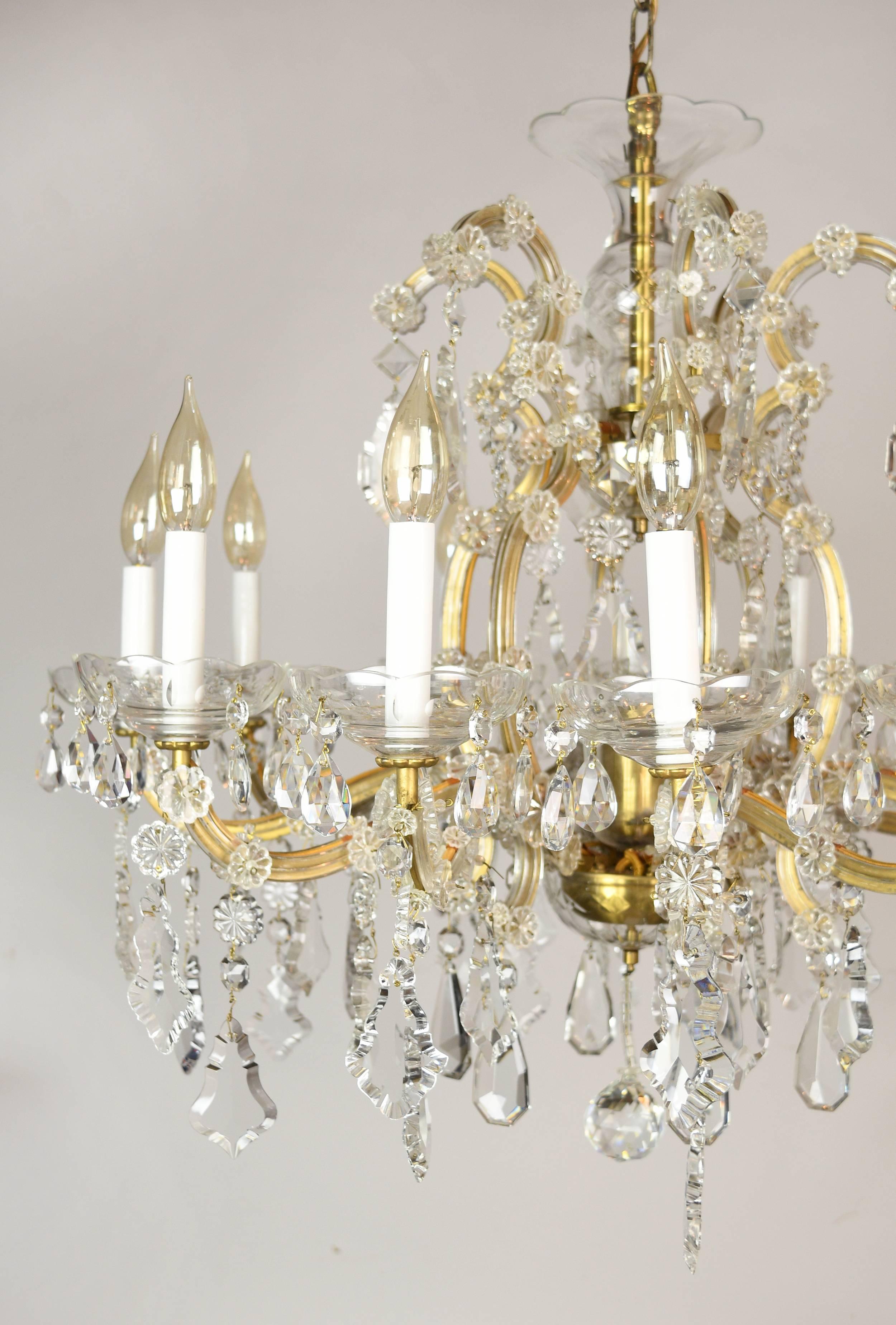 This beautiful 12-arm Maria Theresa crystal chandelier is shiny and heavy, and every arm is draped with numerous glittering crystals of varying shapes and sizes. This fixture would be perfect over a dining room table or in a grand foyer. It’s got