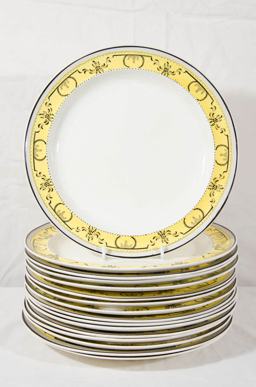 This set of a dozen English creamware dinner dishes made by Davenport have exquisite yellow borders decorated with a black neoclassical design. 
Davenport was known for its dishes with decorative painted borders in many colors. 
Yellow was the