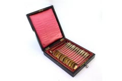 Twelve gilded dessert spoons and sugar tong with reliefs and monogram, cased
