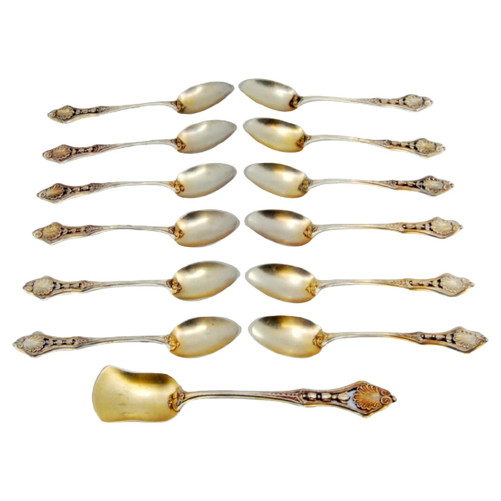 Twelve gilded silver teaspoons and sugar shovel with applied relief handles
