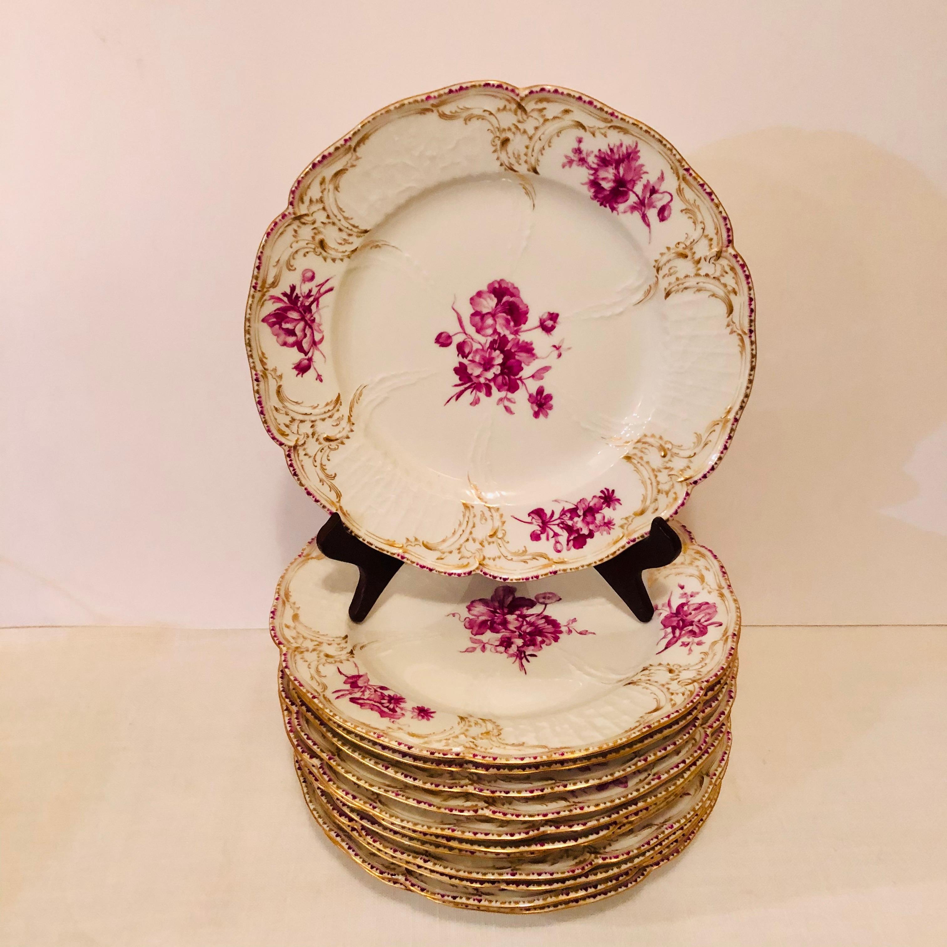 This is an amazing set of twelve KPM dinner plates, each hand-painted with a different puce colored flower bouquets. It has a central flower painting with three different bouquet medallions painted outside the central flower bouquet. You can see the