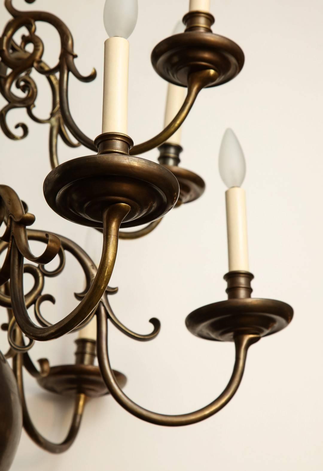 A twelve-light Dutch Baroque style patinated bronze chandelier with ball shaped element, below two tiers of candle arms.