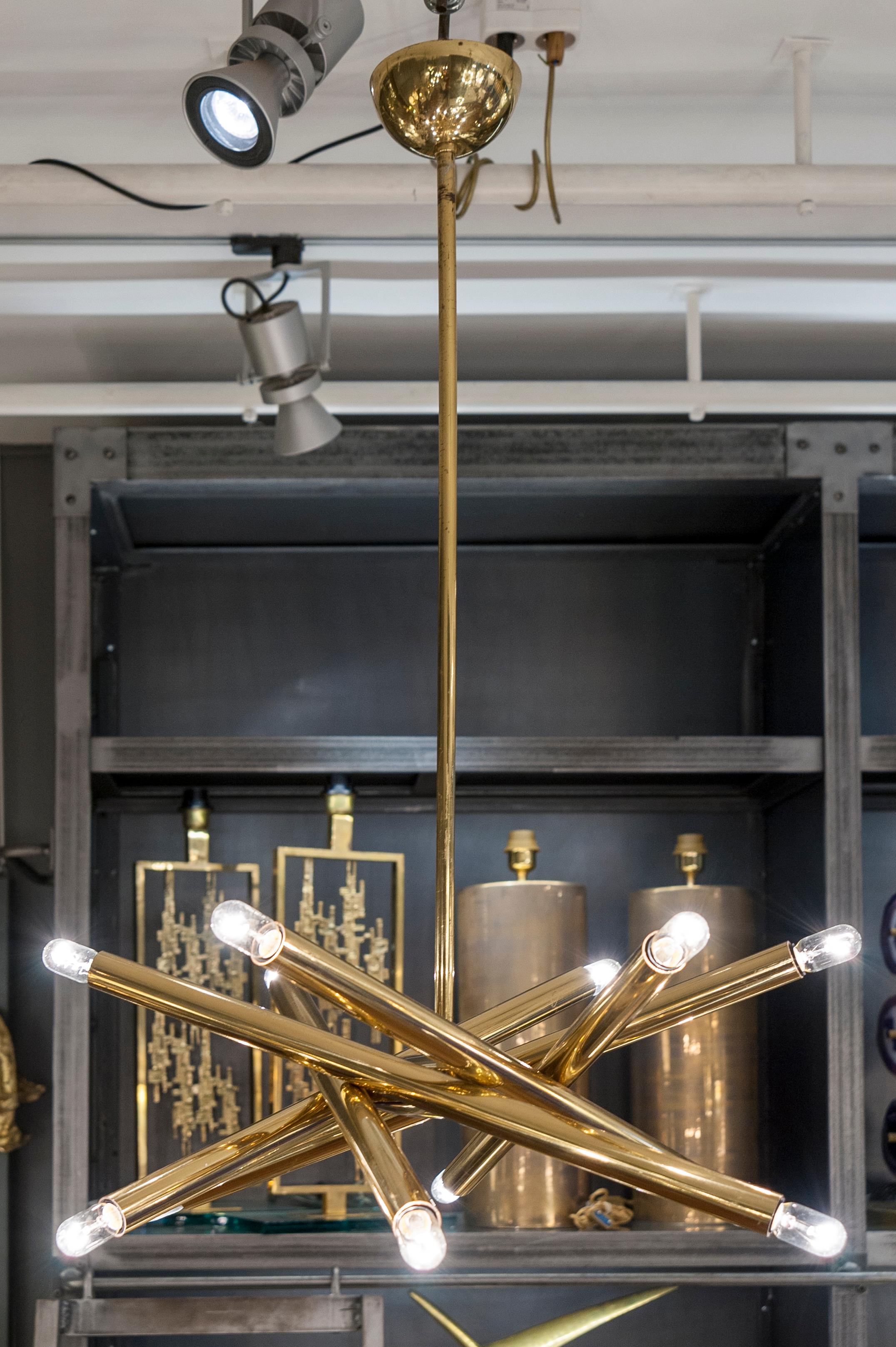 Elegant chandelier made of a six brass rods intertwined, each holding two lights. By Sciolari.
