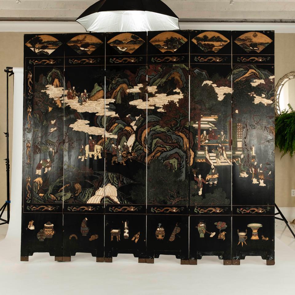 Early 20th century Chinese late Qing dynasty twelve panel lacquered coromandel screen. This grand screen features a landscape scene with pavilions and figures. Each panel measures 17.25 inches wide with thick lacquer. Intricately carved and incised