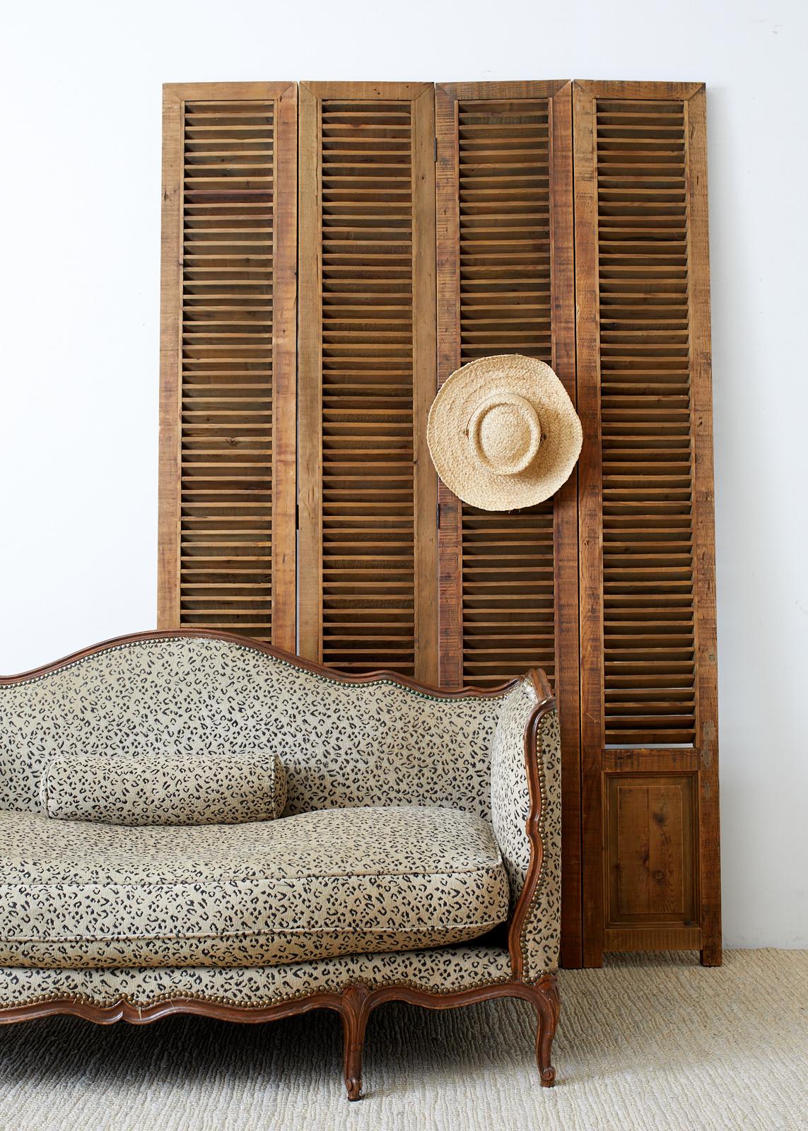 Handsome folding screen made of twelve pine panels each with a louvered window measuring 9 inches wide and 65 inches high. The shutter window style panels are in three sets of four panels measuring 13.75 inches wide for a total width of 165 inches
