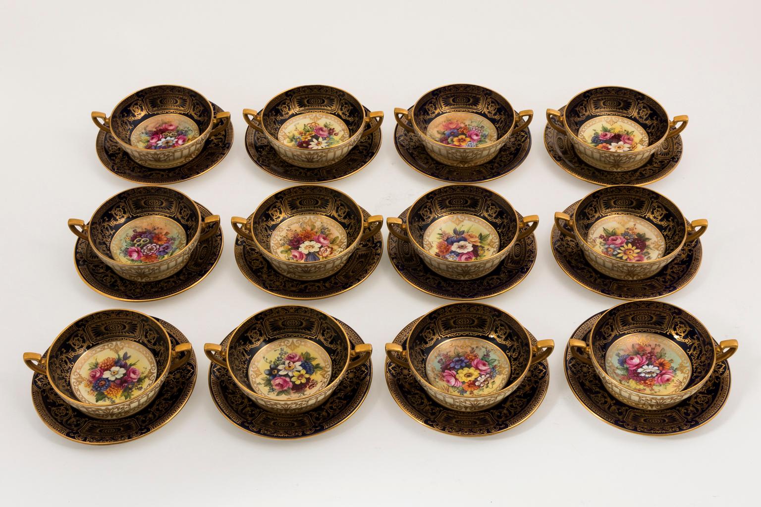Set of twelve Bullion cups with under plates by Royal Worcester, circa early 20th century. Each cup and under plate is hand-painted with floral motifs, gilded detail, and cobalt blue borders. Artist signed. The cups measure 6.75 inches wide by 4.75